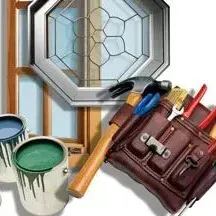 A hammer , brushes , paint , and a tool bag are sitting next to a stained glass window.