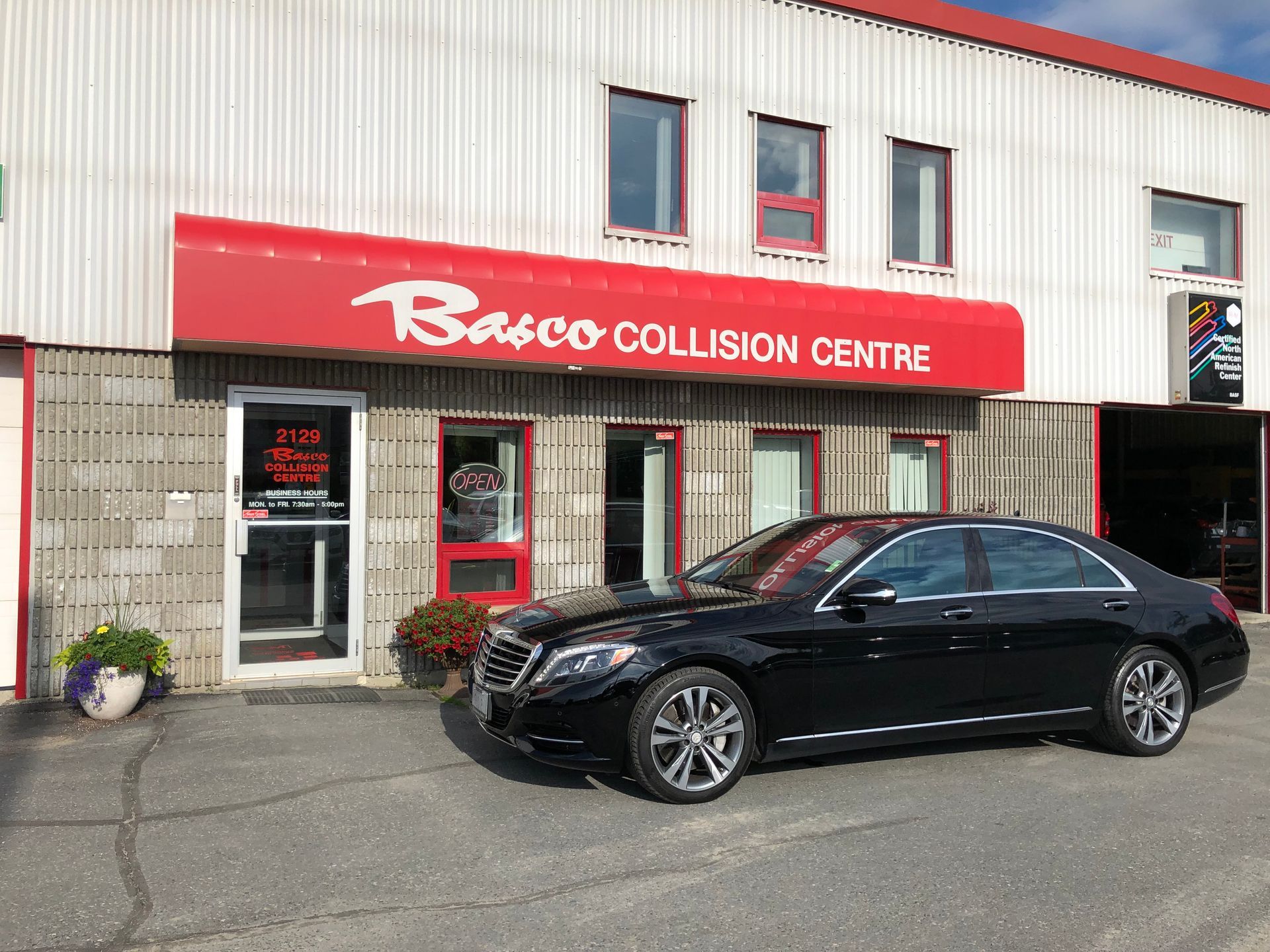 A black car is parked in front of a building.