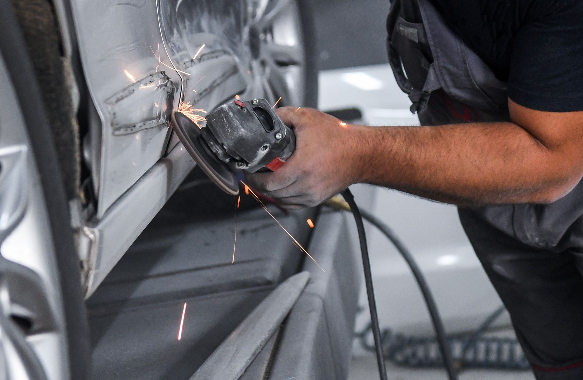 A man is grinding a car door with a grinder.