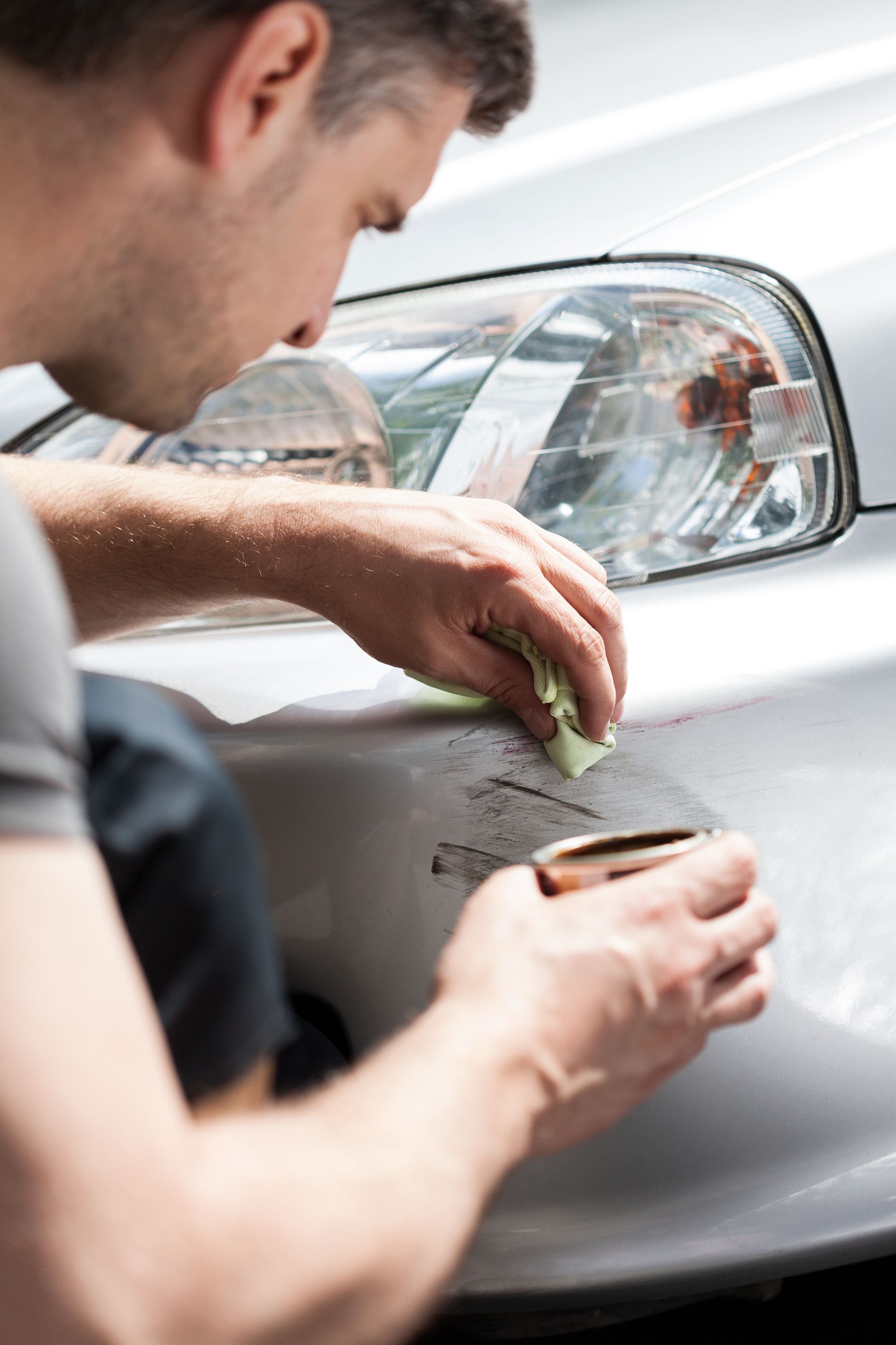 A man is cleaning a car with a cloth.