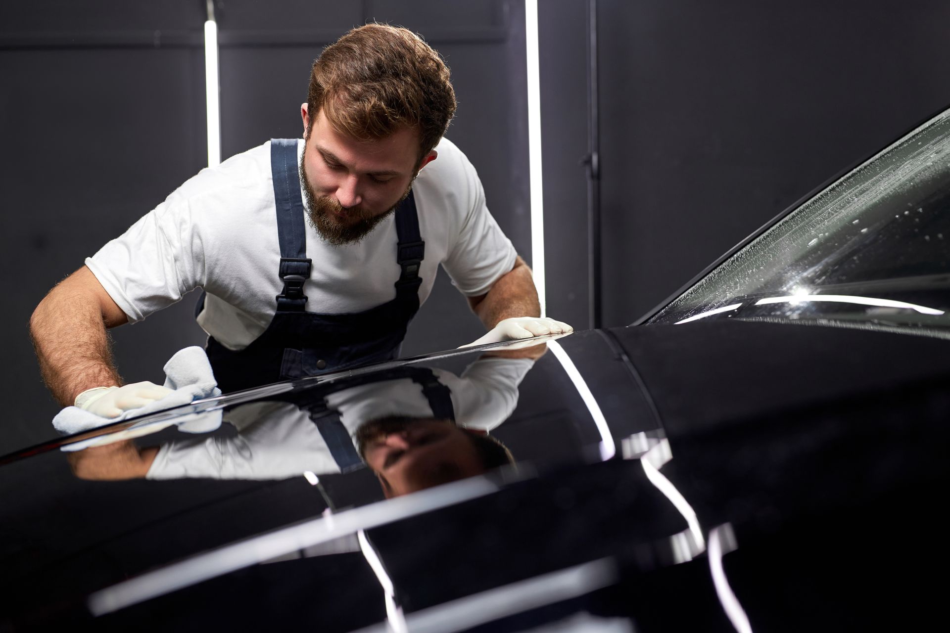 Detailing a black car with a polishing cloth in a workshop