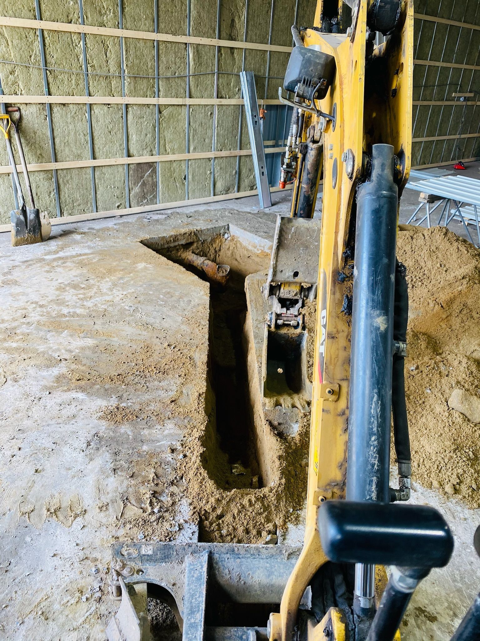 Une excavatrice jaune creuse un trou dans le sol.