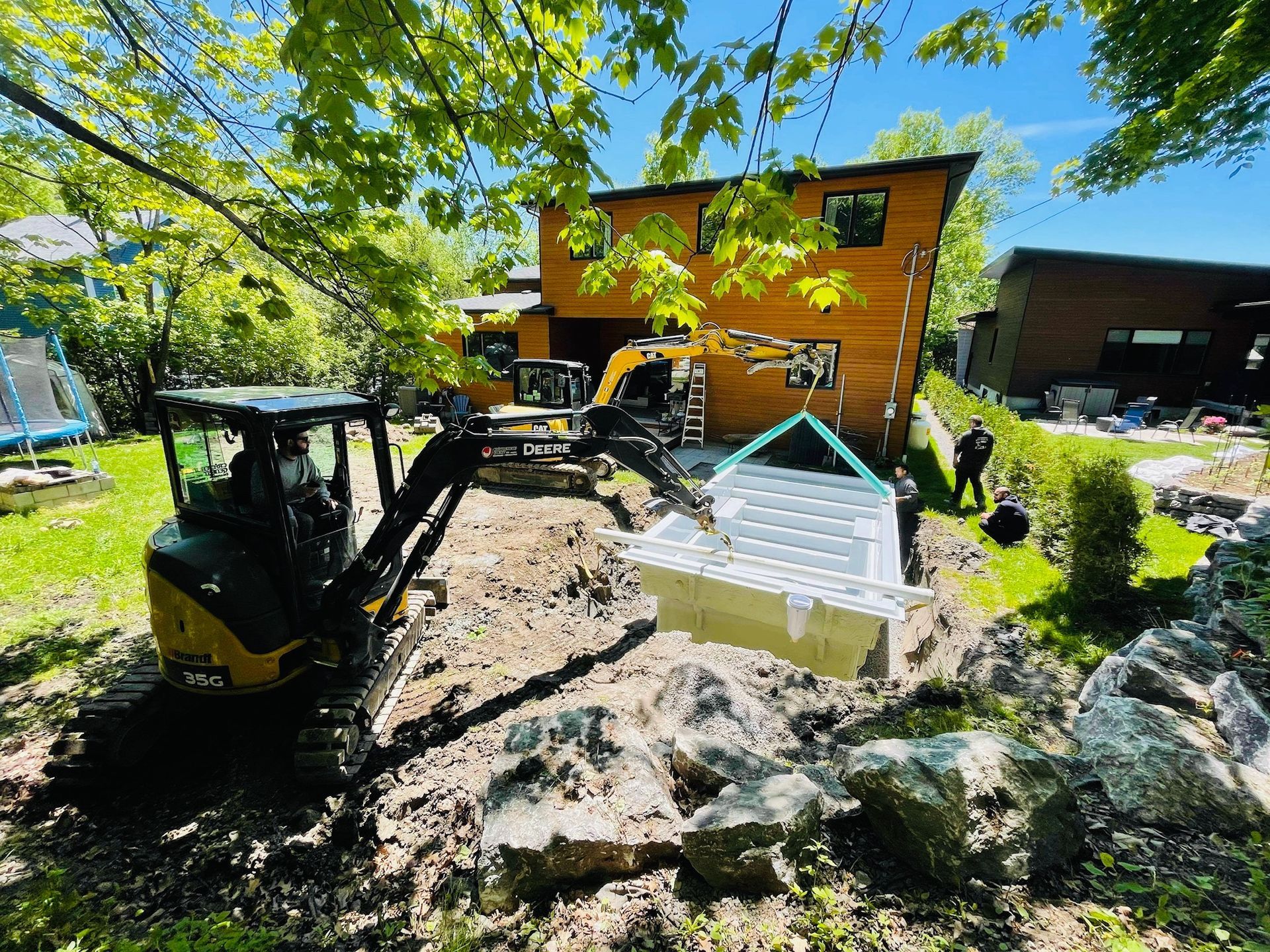 Un jacuzzi est soulevé par un bulldozer devant une maison.