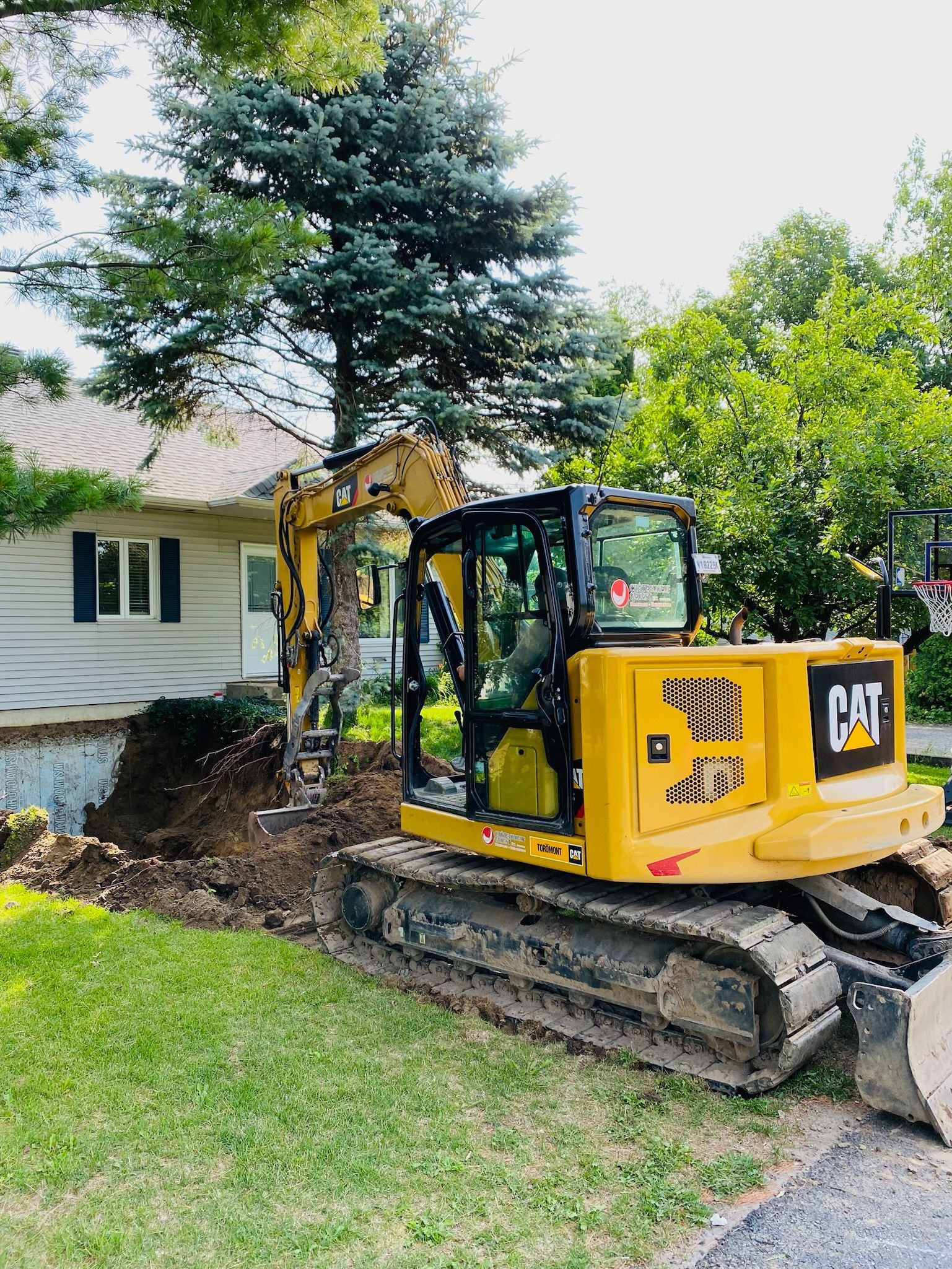 Une excavatrice jaune est assise devant une maison.