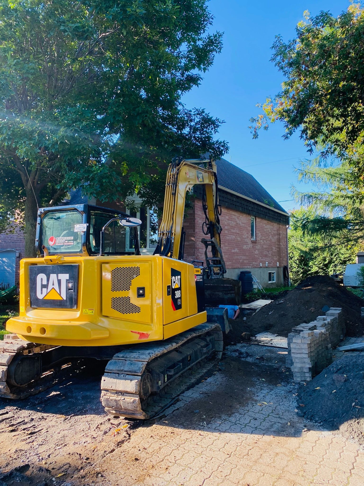 Une excavatrice jaune est assise devant une maison.