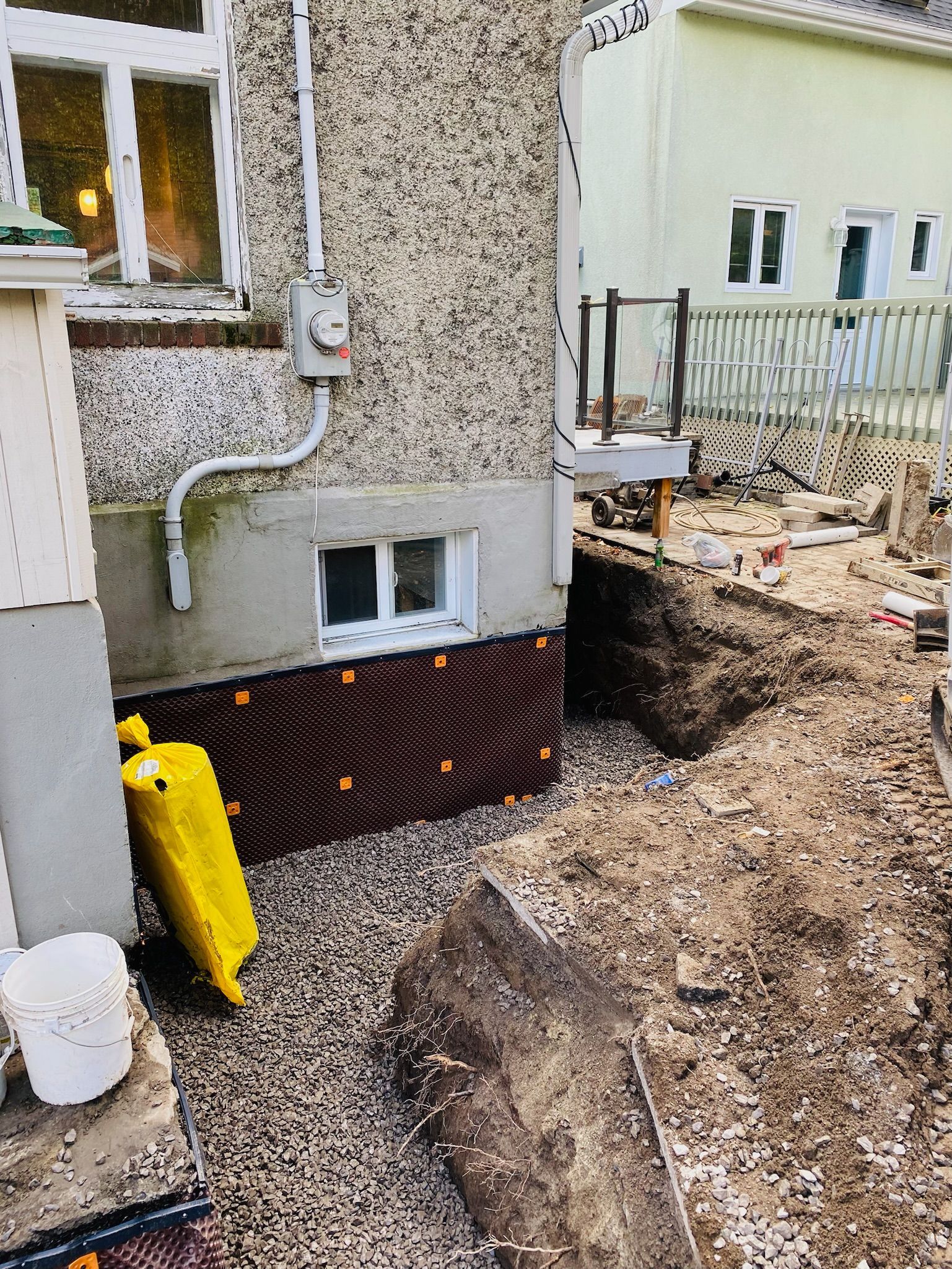 Un seau jaune est posé devant une maison.