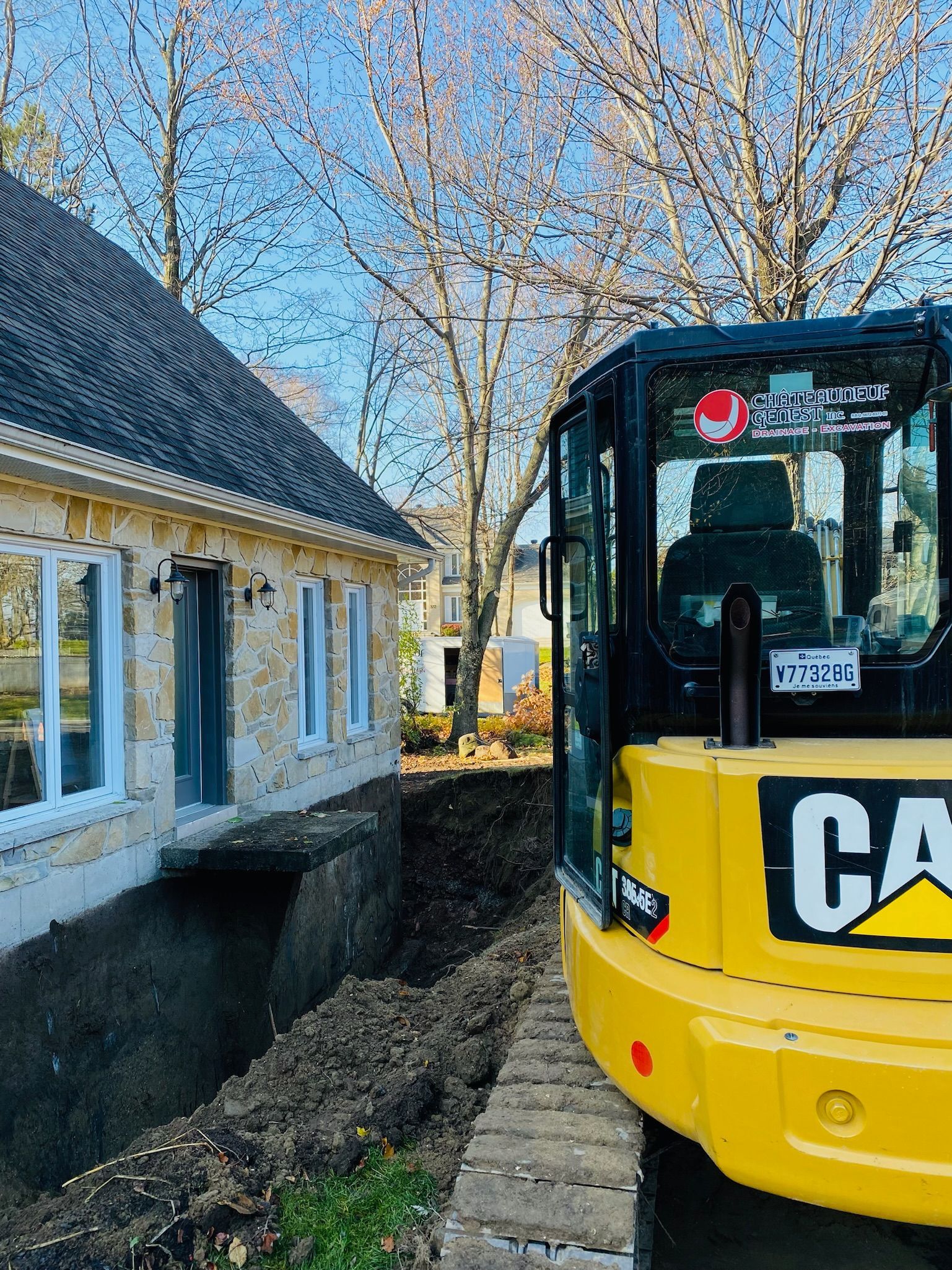 Une excavatrice jaune est garée devant une maison.