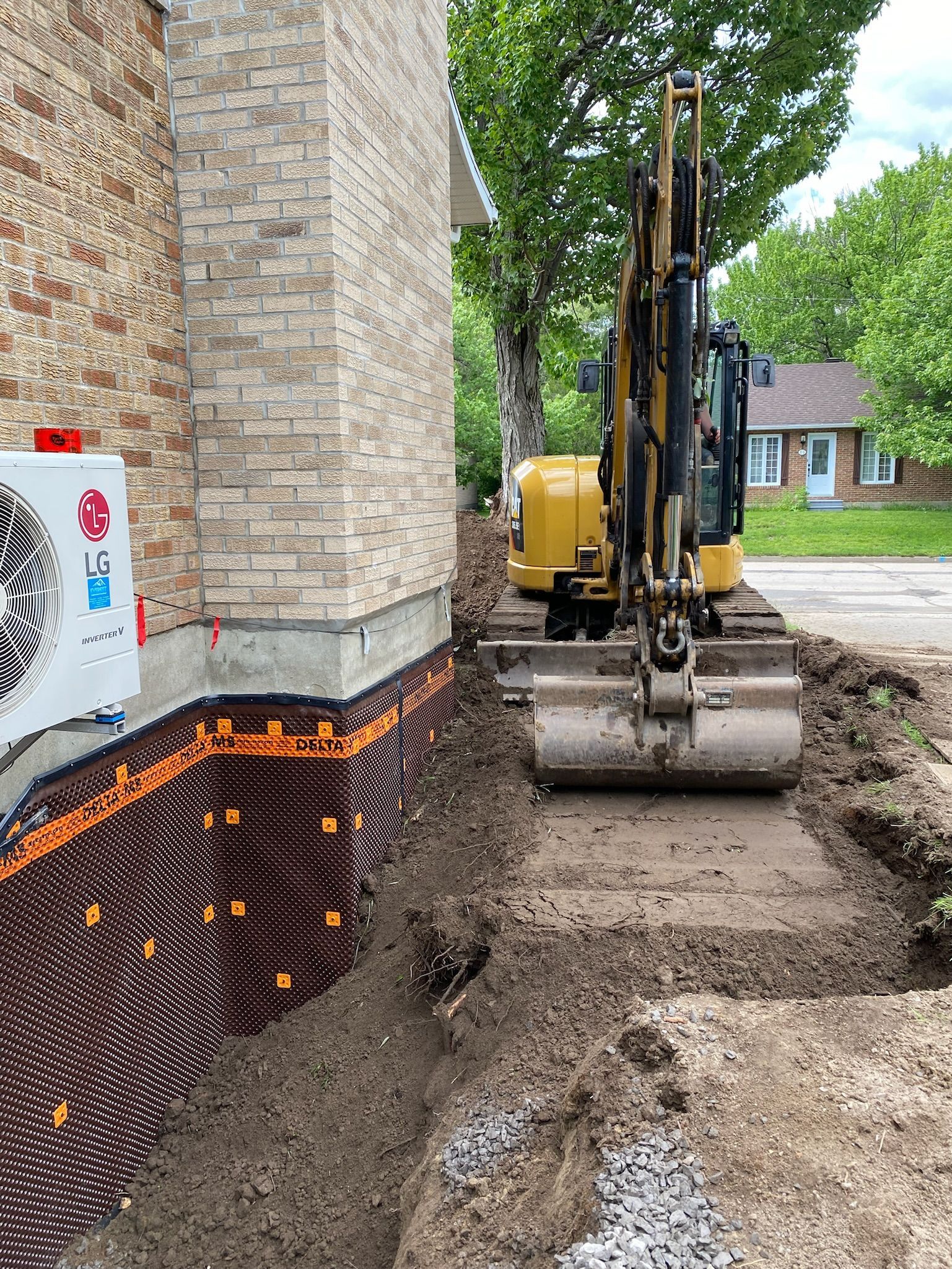 Un bulldozer creuse un trou devant un bâtiment en briques.