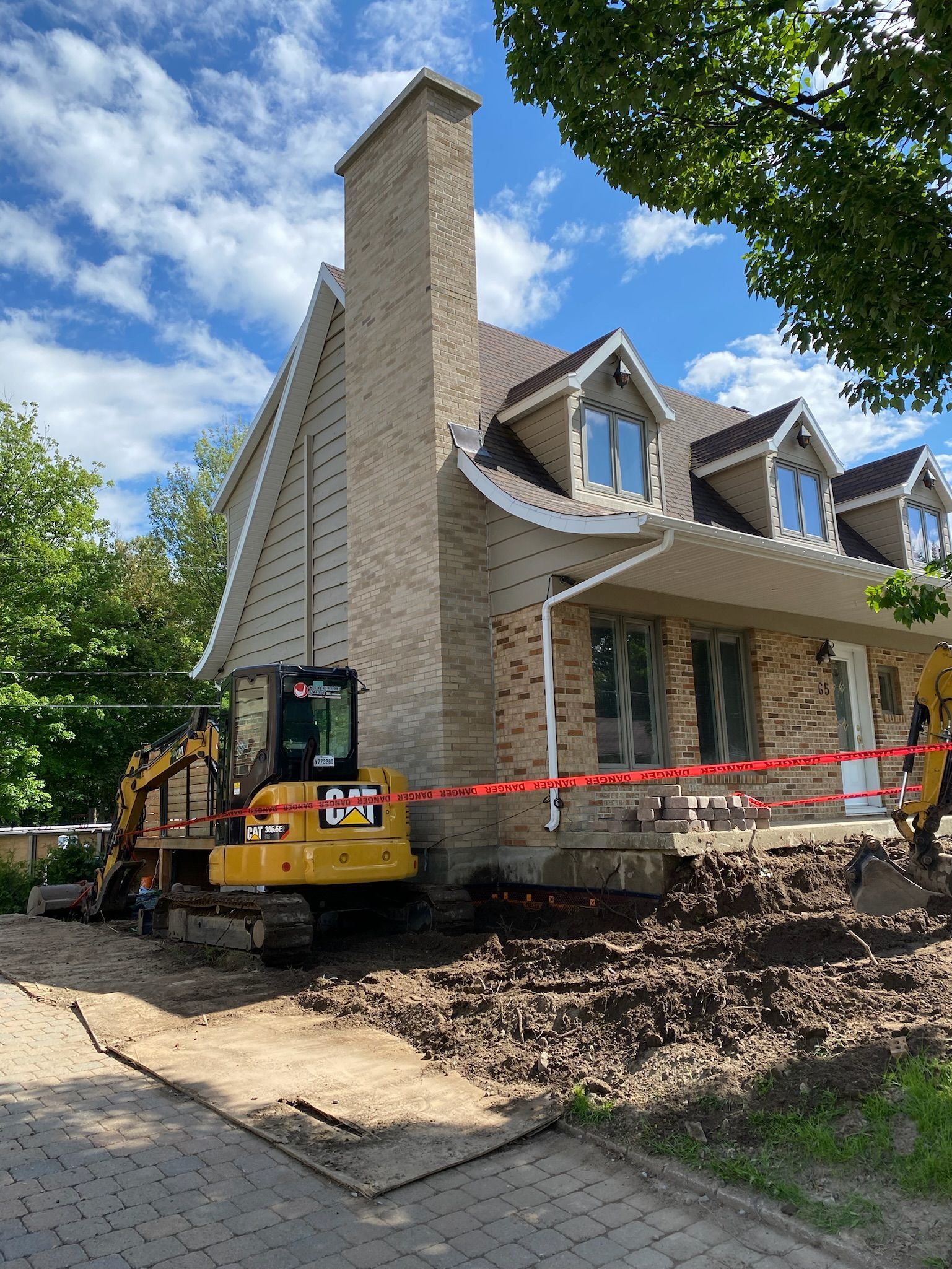 Une maison est en cours de rénovation avec une excavatrice jaune devant elle.