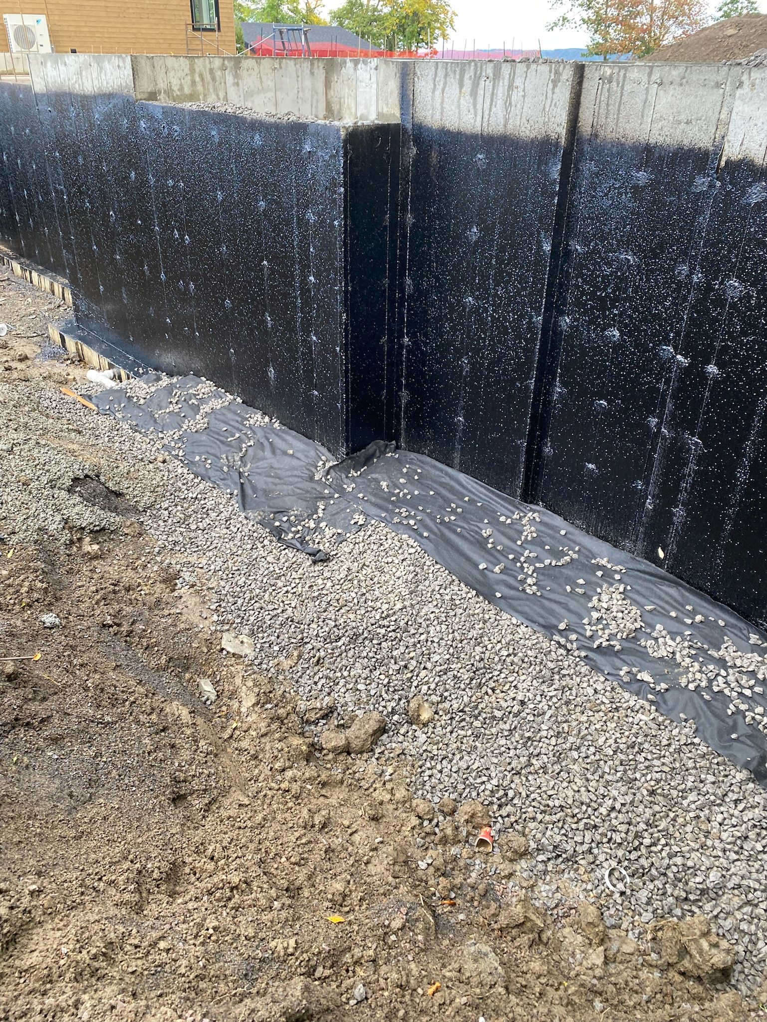 Un mur noir est entouré de gravier et de terre.