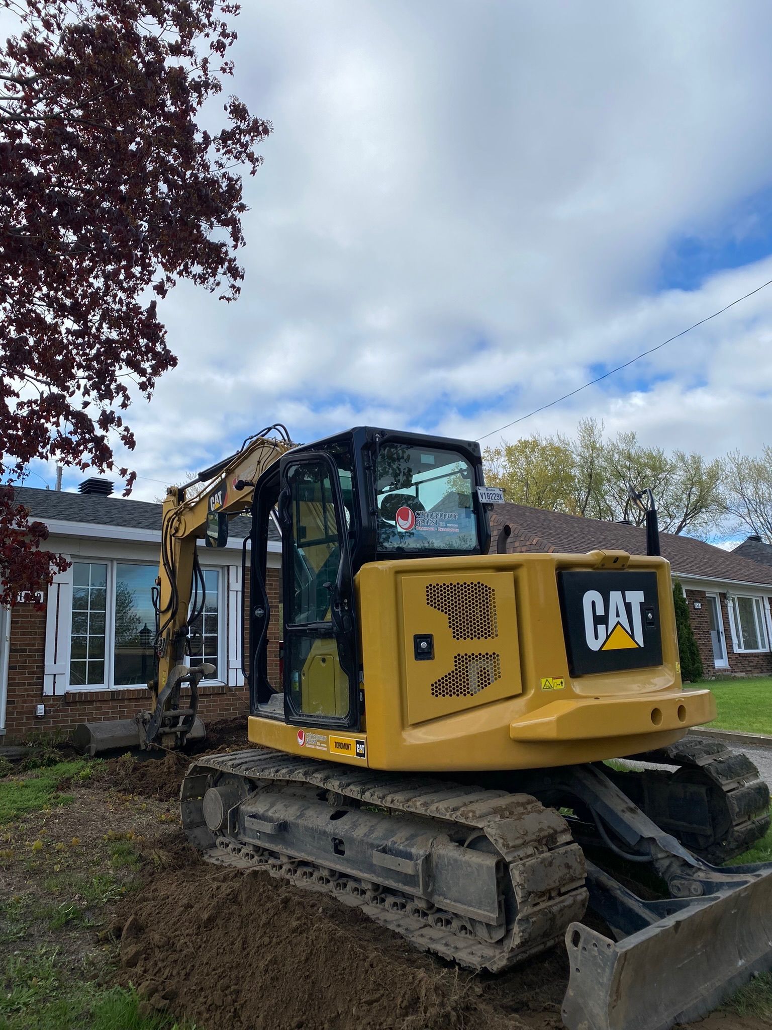 Une excavatrice à chat est assise devant une maison.