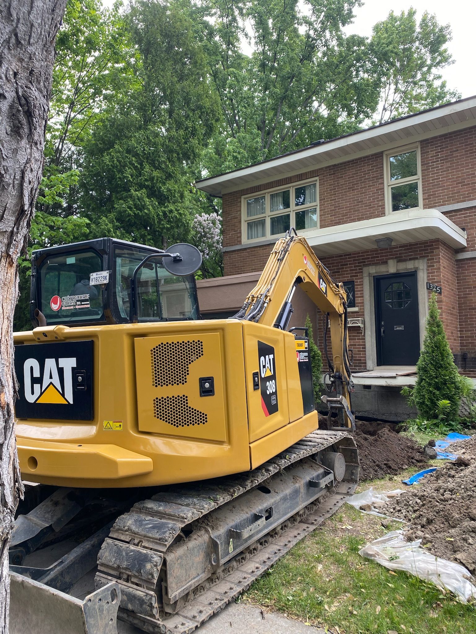 Une excavatrice à chat jaune est assise devant une maison en briques.