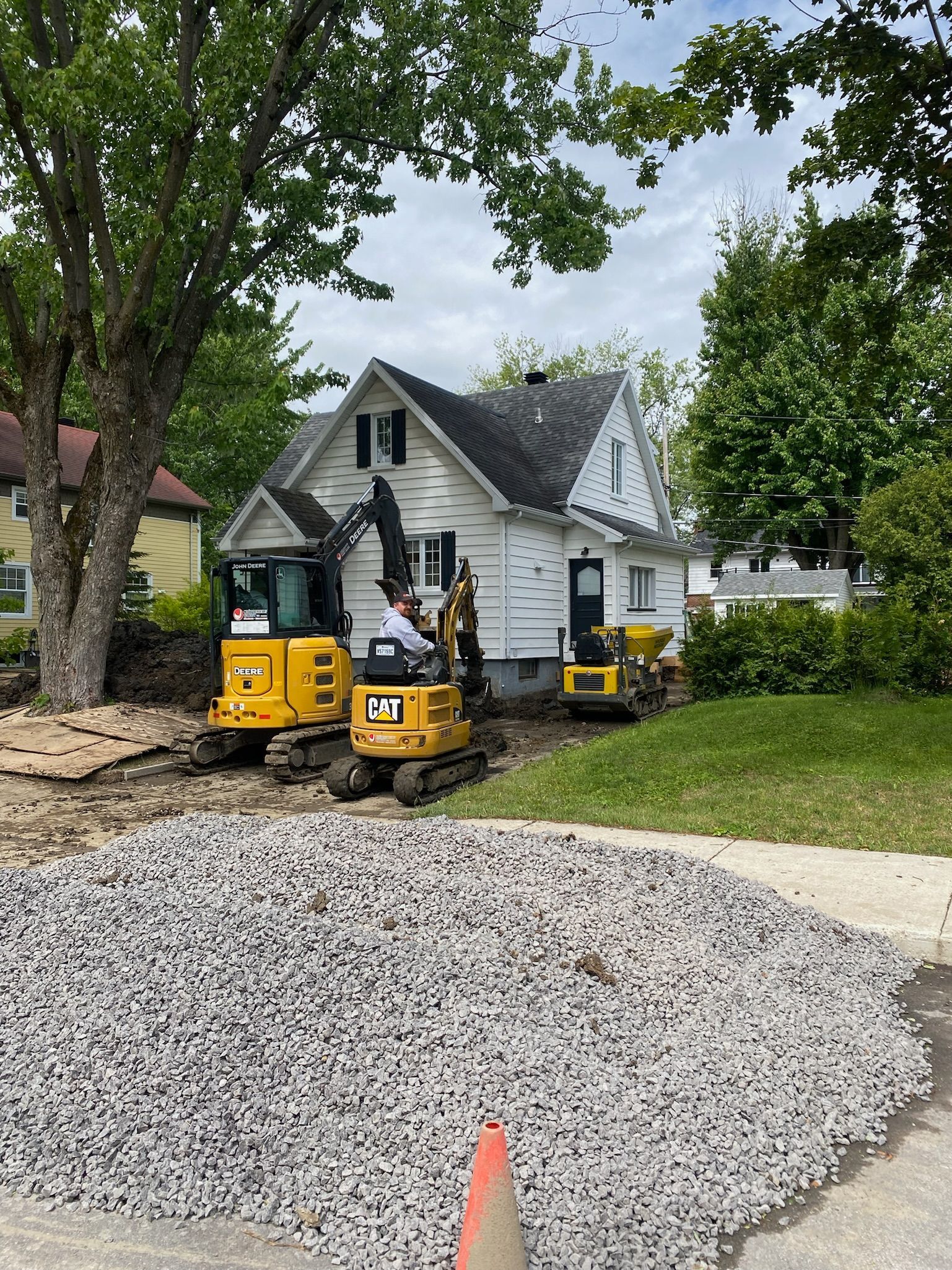 Un couple d'excavatrices travaille devant une maison.
