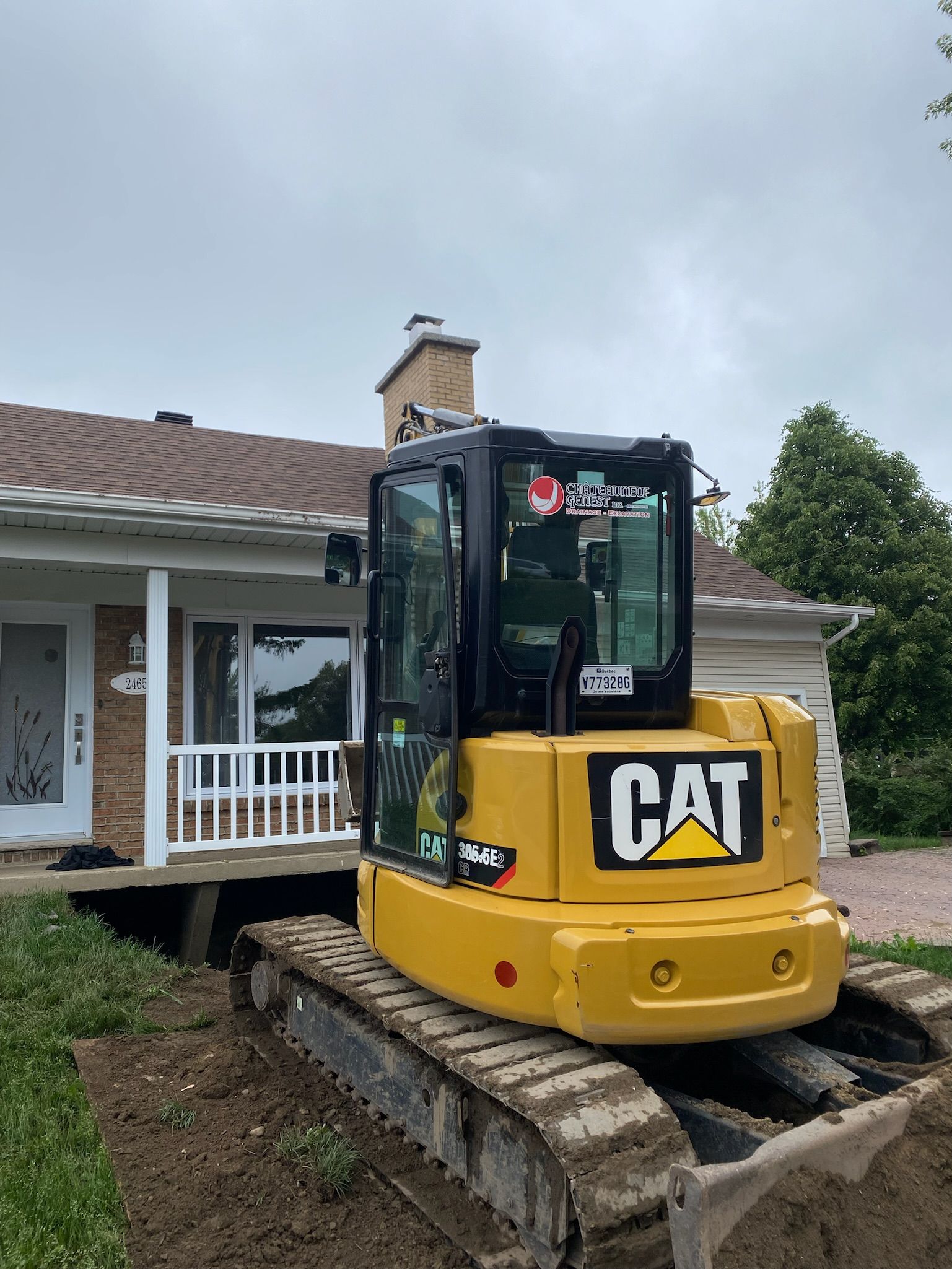 Une excavatrice jaune est garée devant une maison.