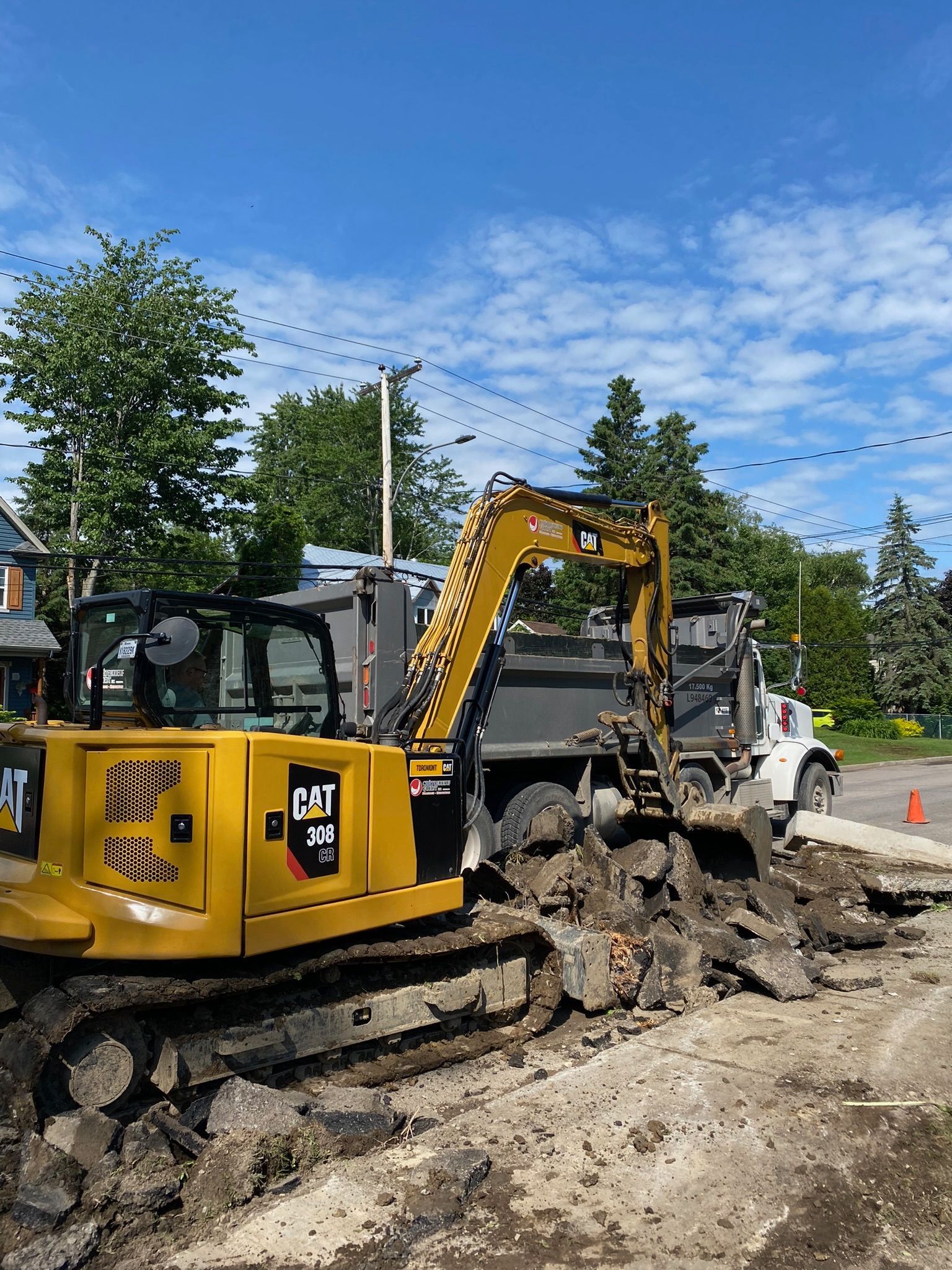 Une excavatrice jaune creuse un trou dans le sol à côté d'un camion à benne basculante.