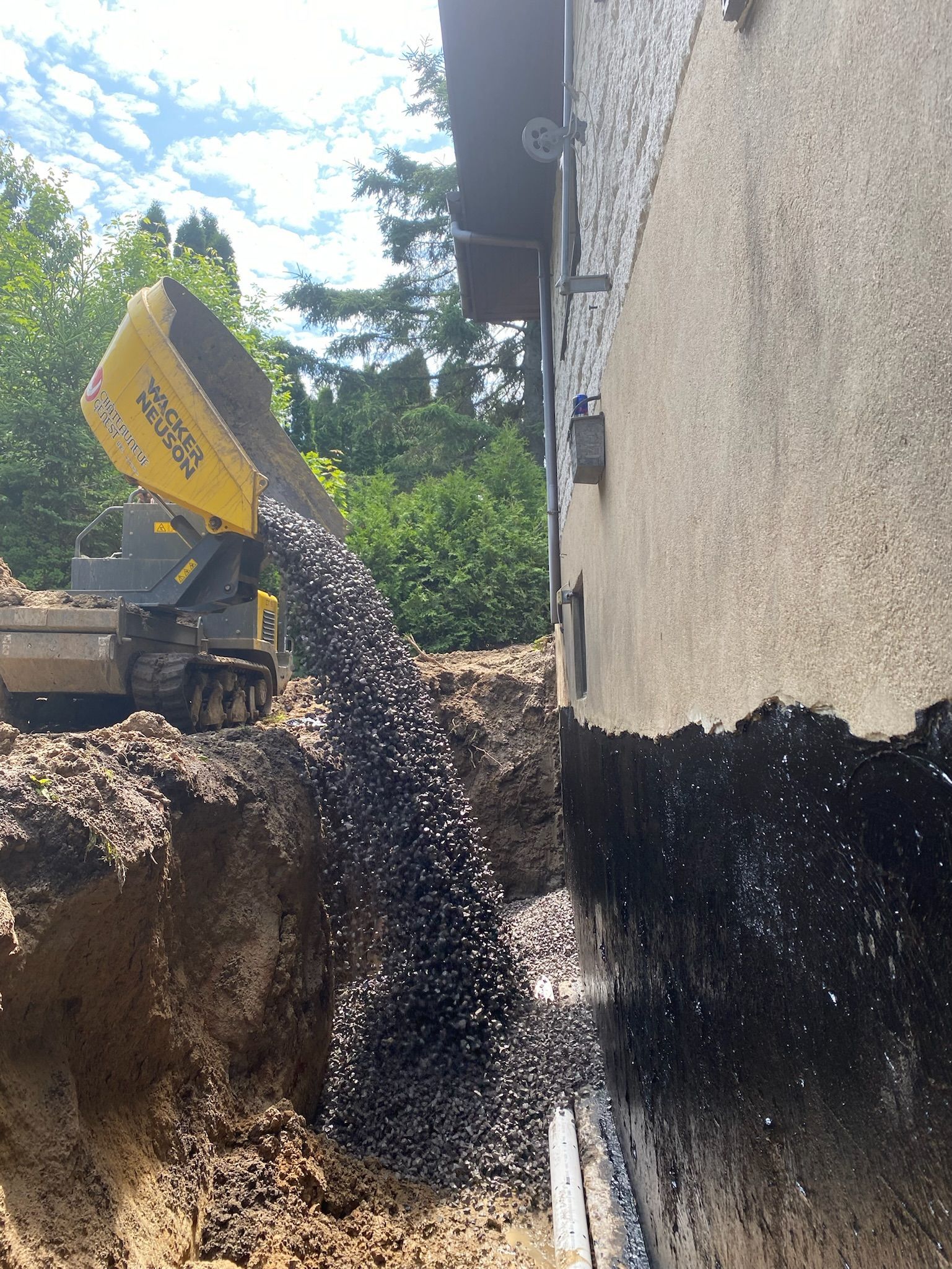 Un camion à benne basculante déverse de la terre dans un trou à côté d'un bâtiment.