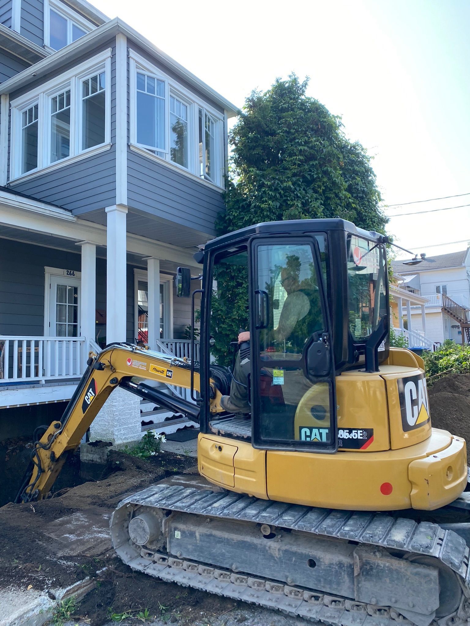 Une excavatrice jaune est garée devant une maison.