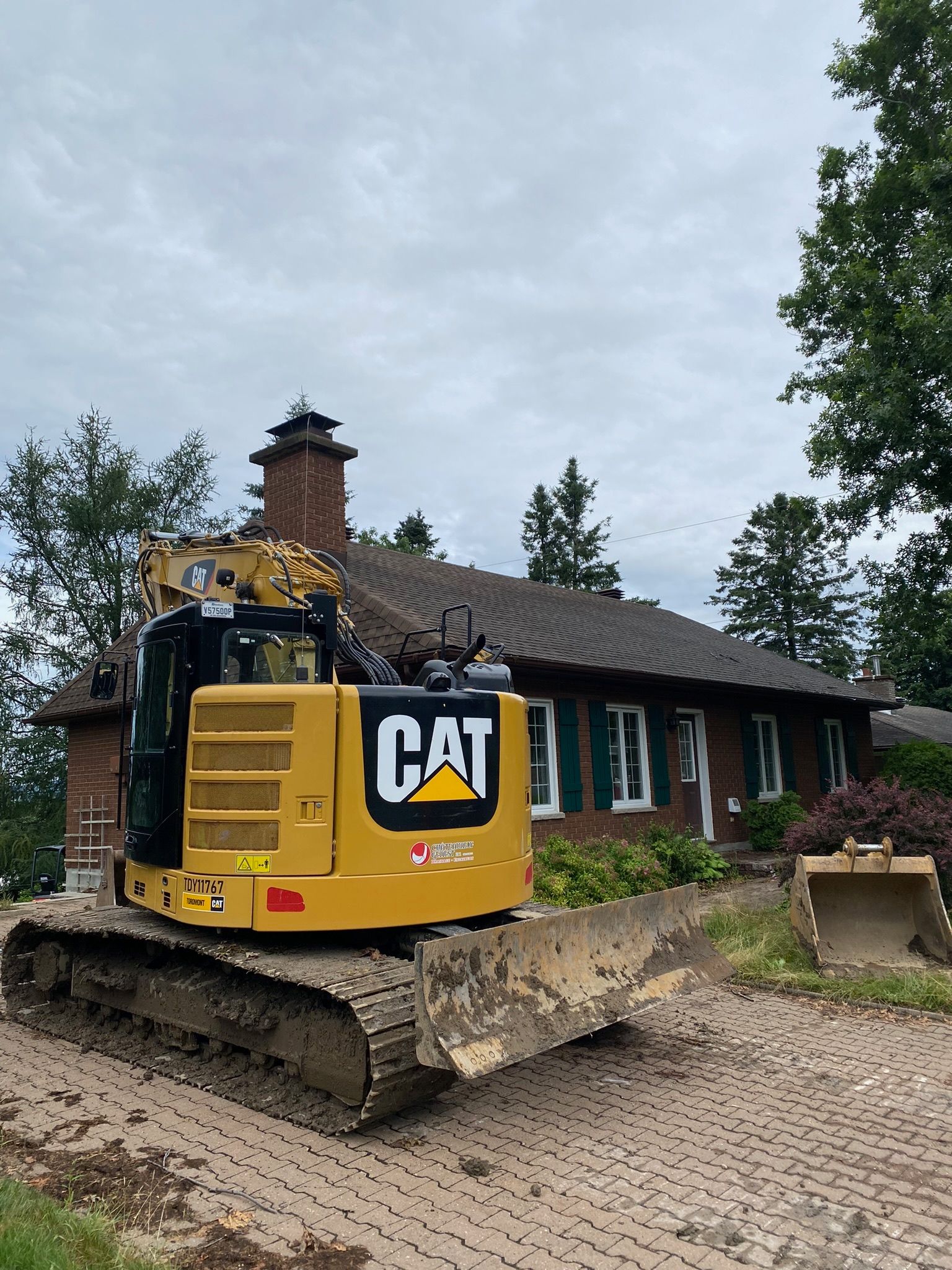 Une excavatrice à chat est garée devant une maison.