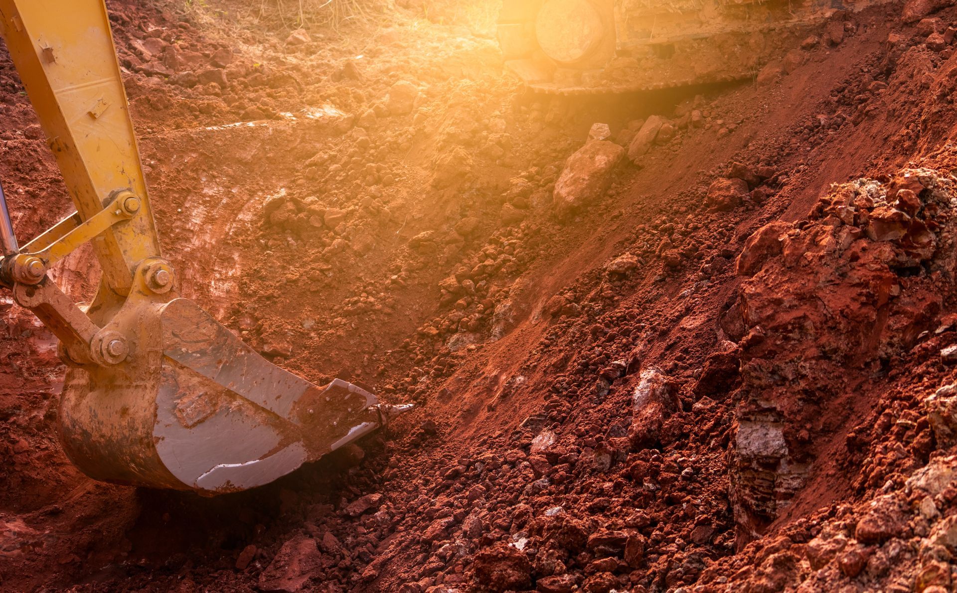 Une excavatrice jaune creuse un trou dans le sol.