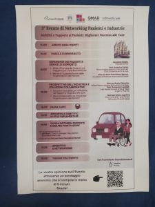 Manifesto per un evento di networking. Mostra il programma con argomenti e relatori. Illustrazione di una persona in sedia a rotelle vicino a un'auto.