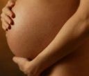 Pancia incinta, pelle scura, mani che cullano l'addome.