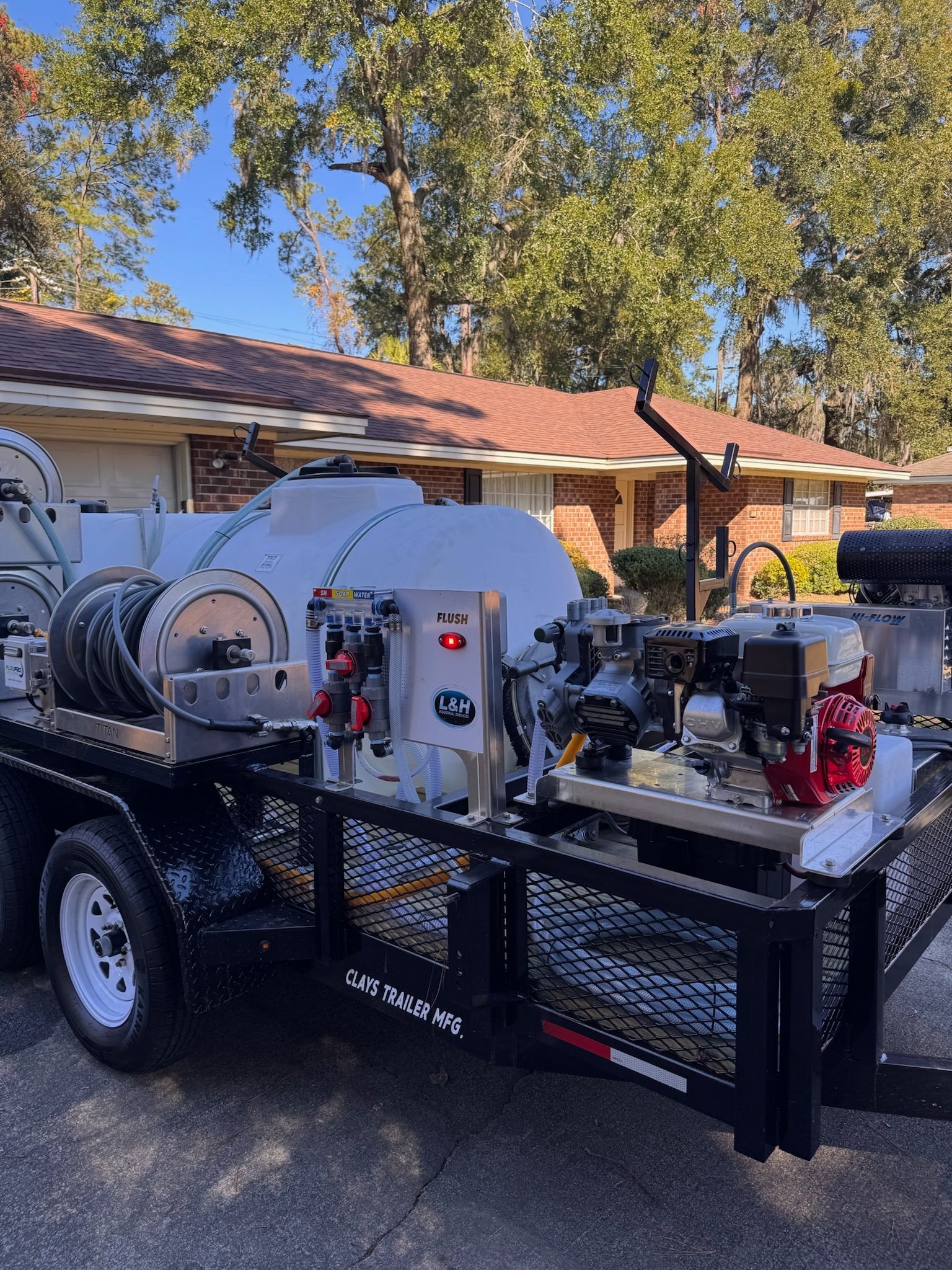 Trailer with large water tank and machinery in front of a house.