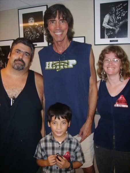 A group of people posing for a picture with Tom Scholz, the leader f the band Boston