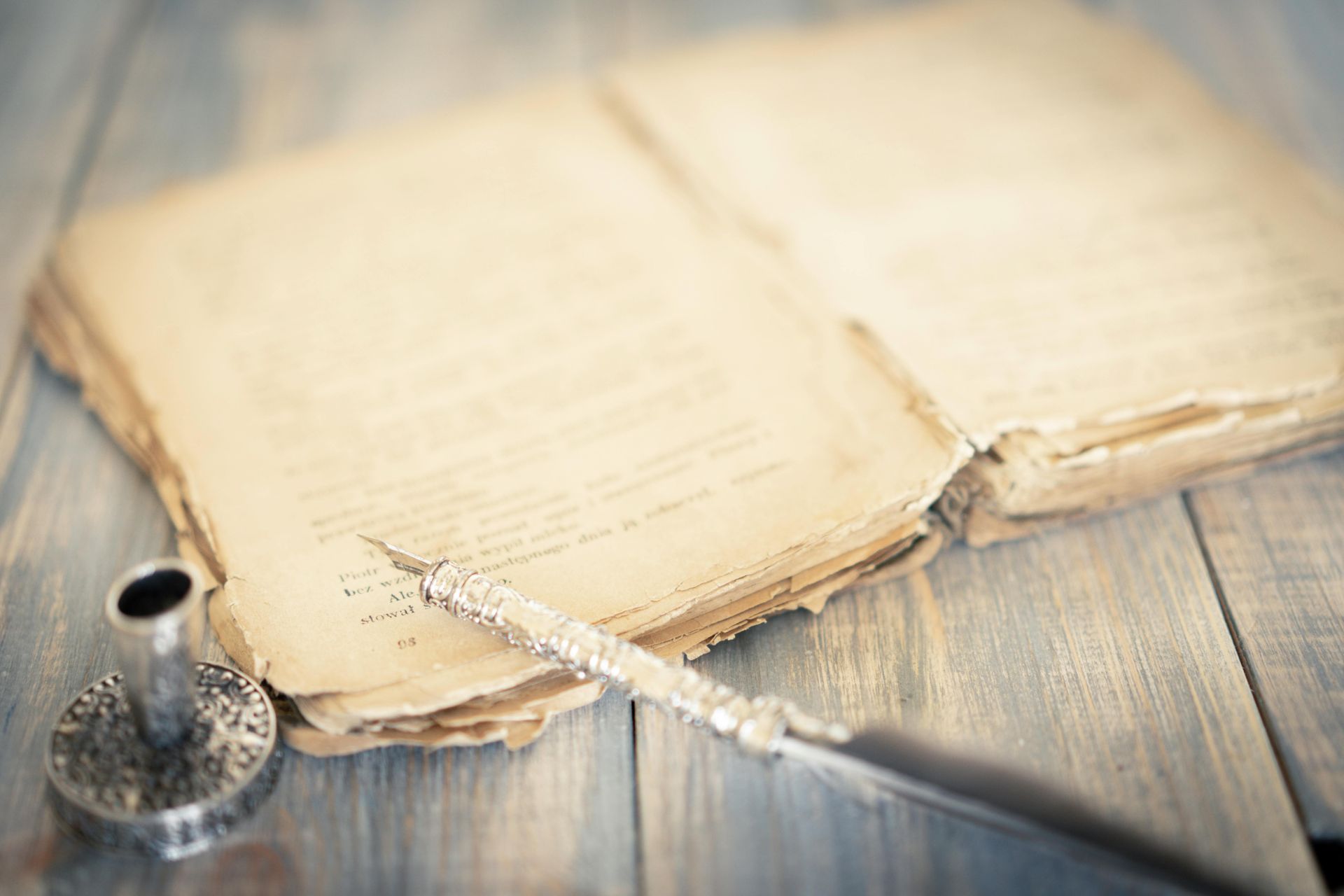 A fountain pen is sitting on top of an open book on a wooden table.