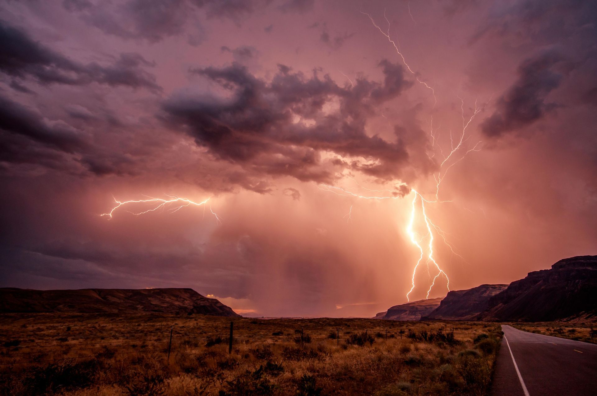 There is a lightning storm over a desert road.