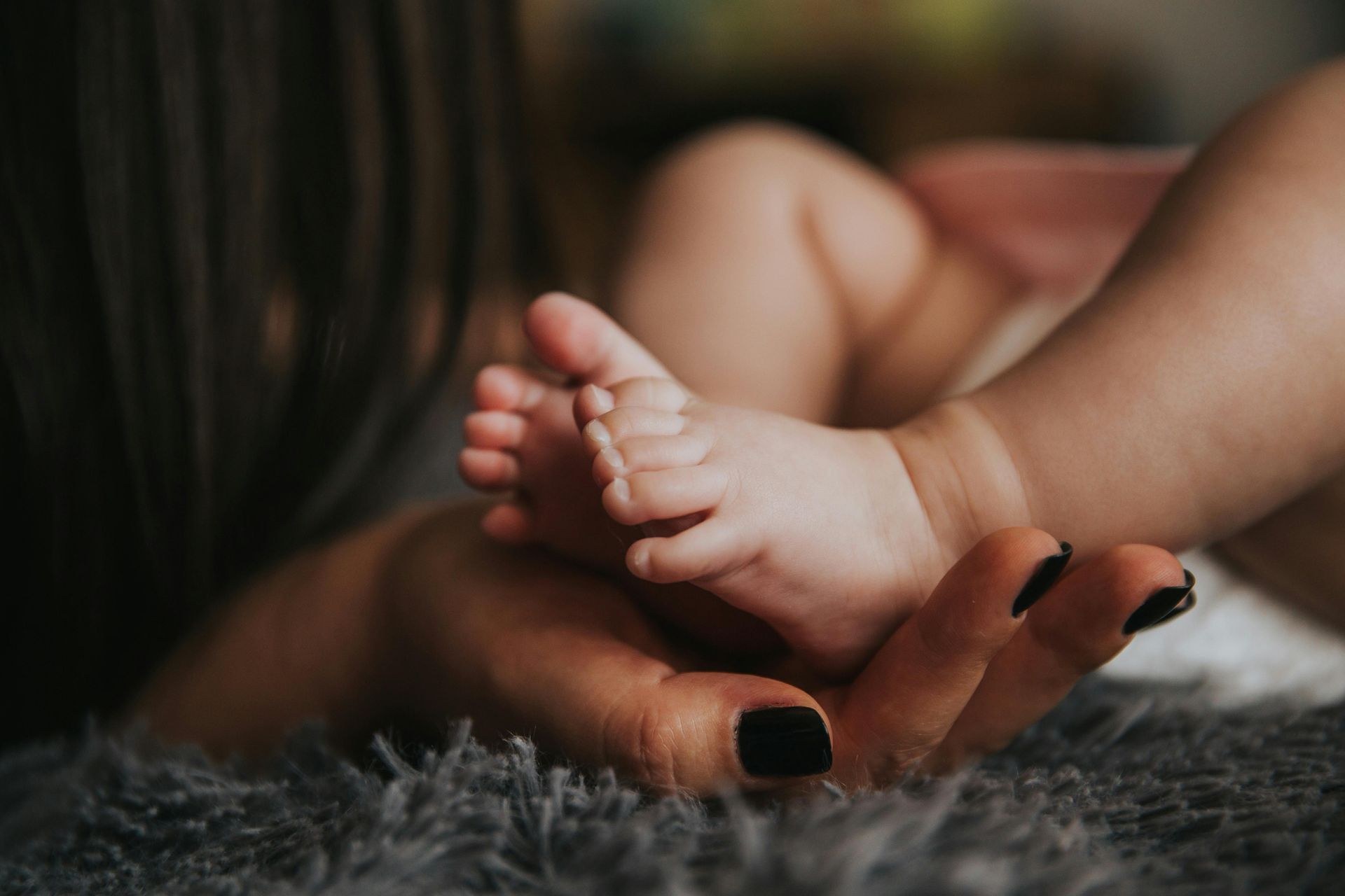 A woman is holding a baby 's foot in her hands.