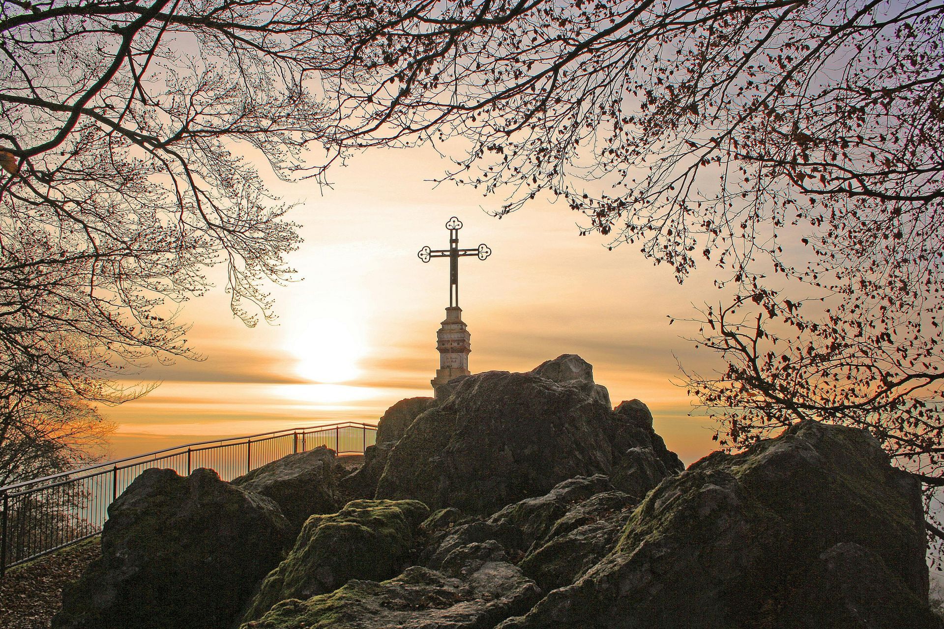 A cross on top of a rocky hill at sunset