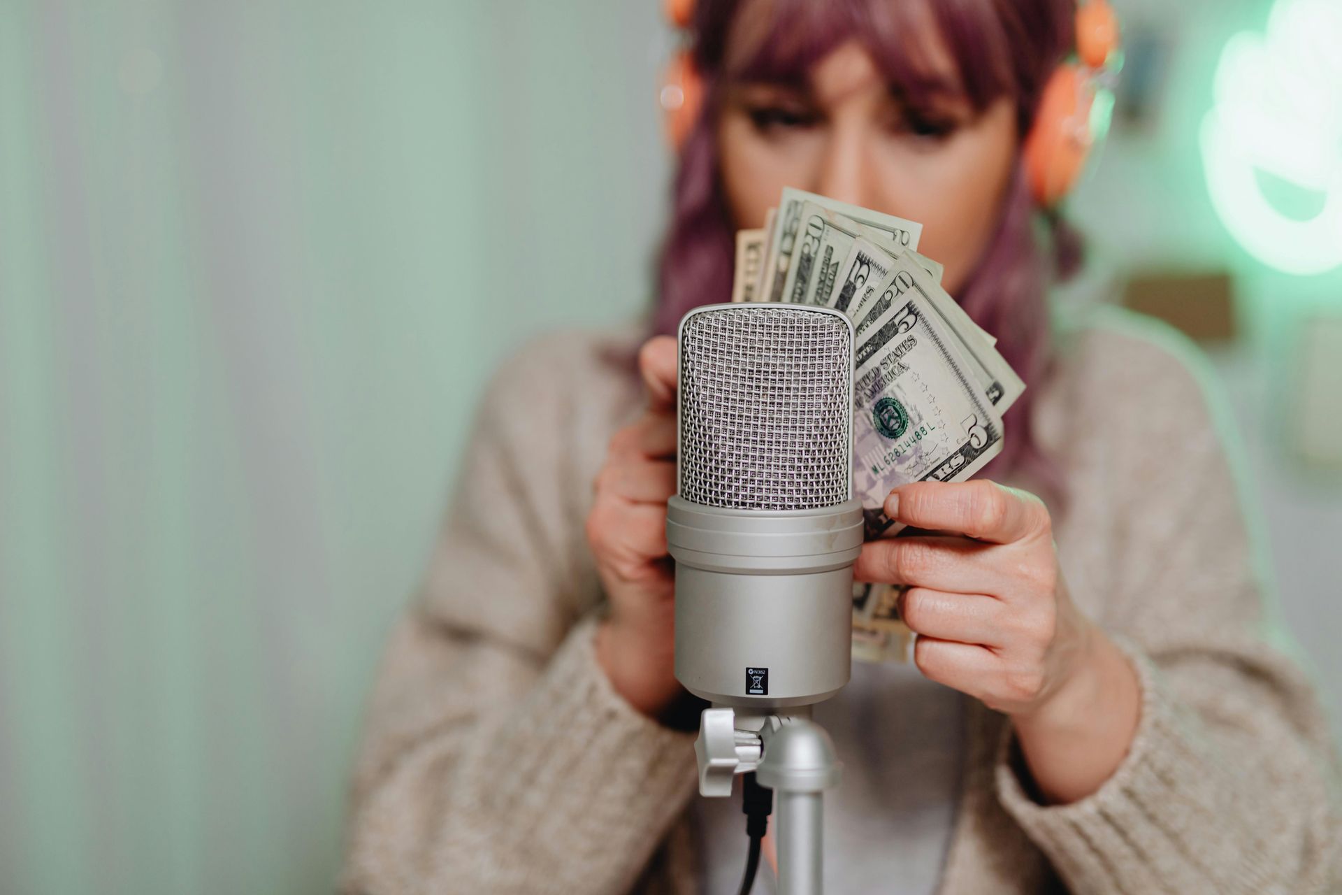 A woman is holding money in front of a microphone.