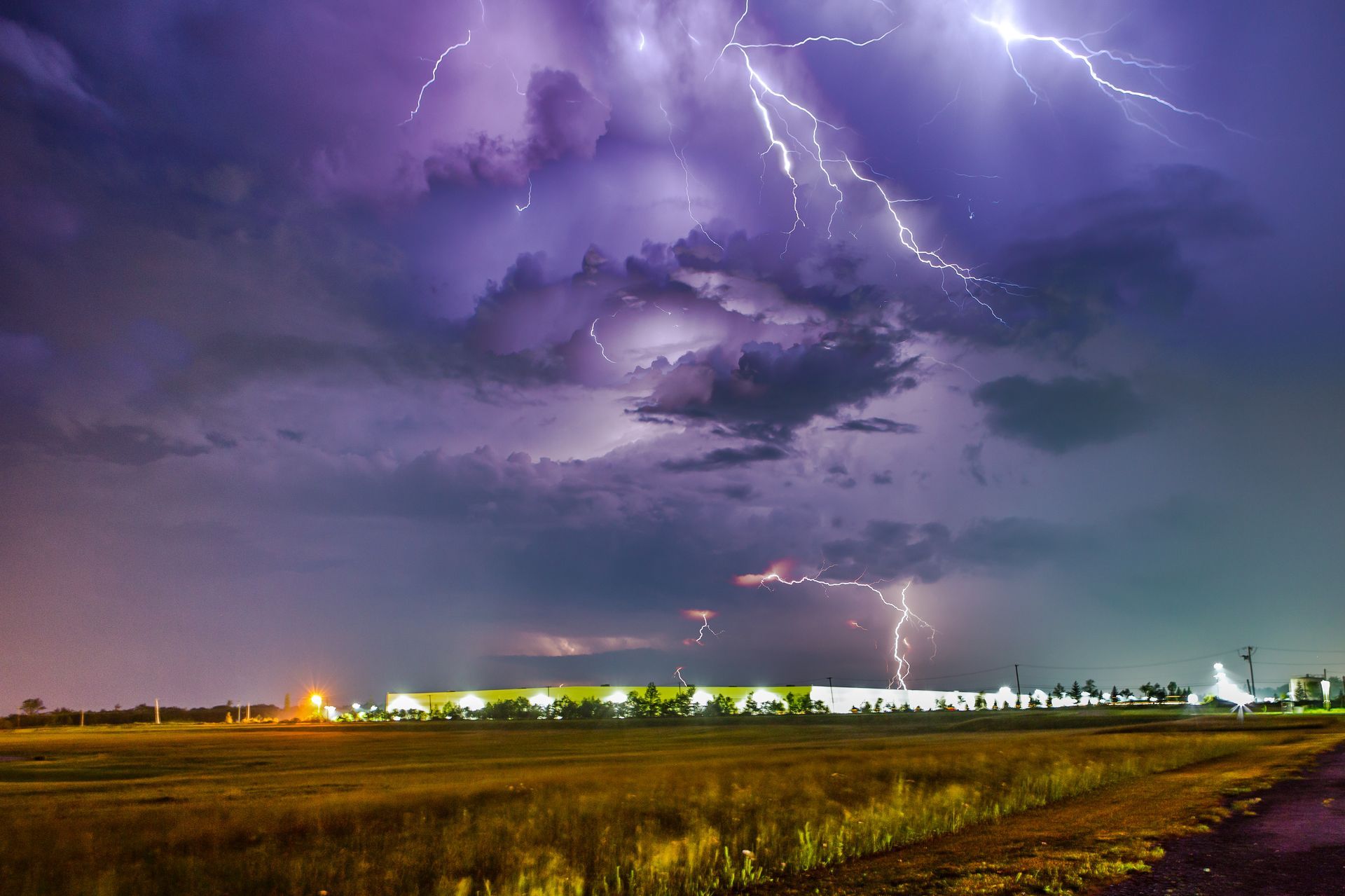 There is a lot of lightning in the sky over a field.