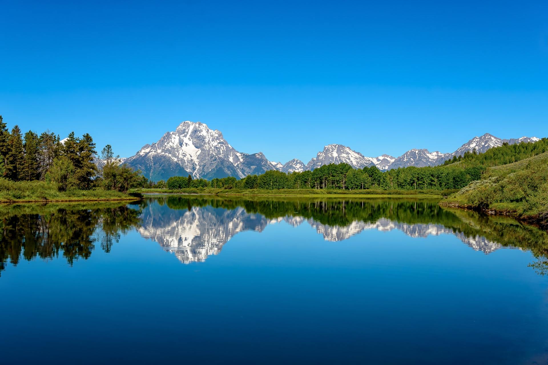 A lake with mountains in the background and trees on the shore