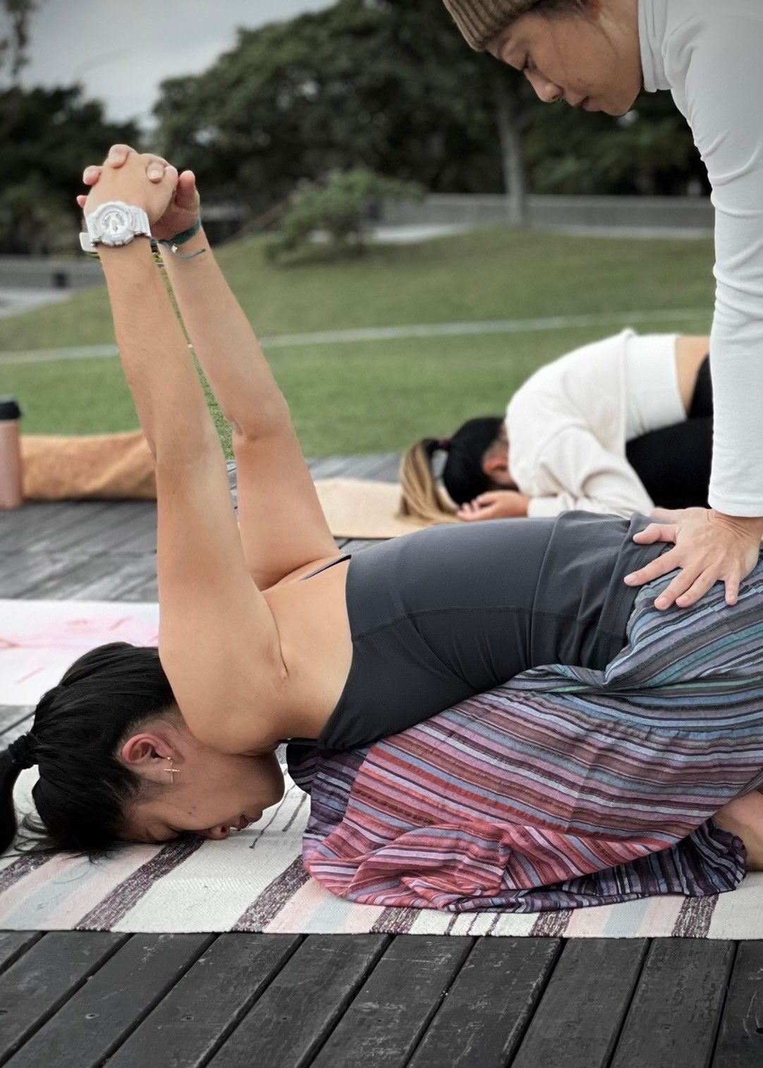 A woman is laying on a yoga mat while another woman helps her.