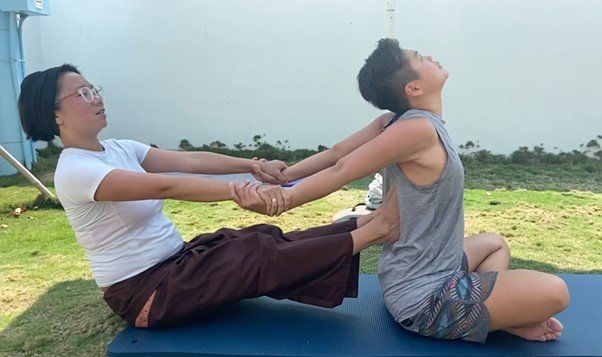 A woman is giving a massage to another woman on a yoga mat.