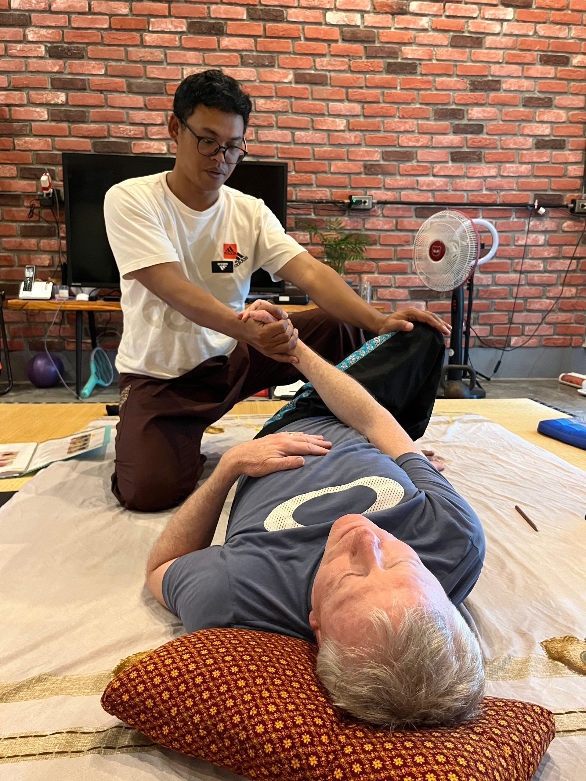 A man is giving a massage to a man laying on a bed.