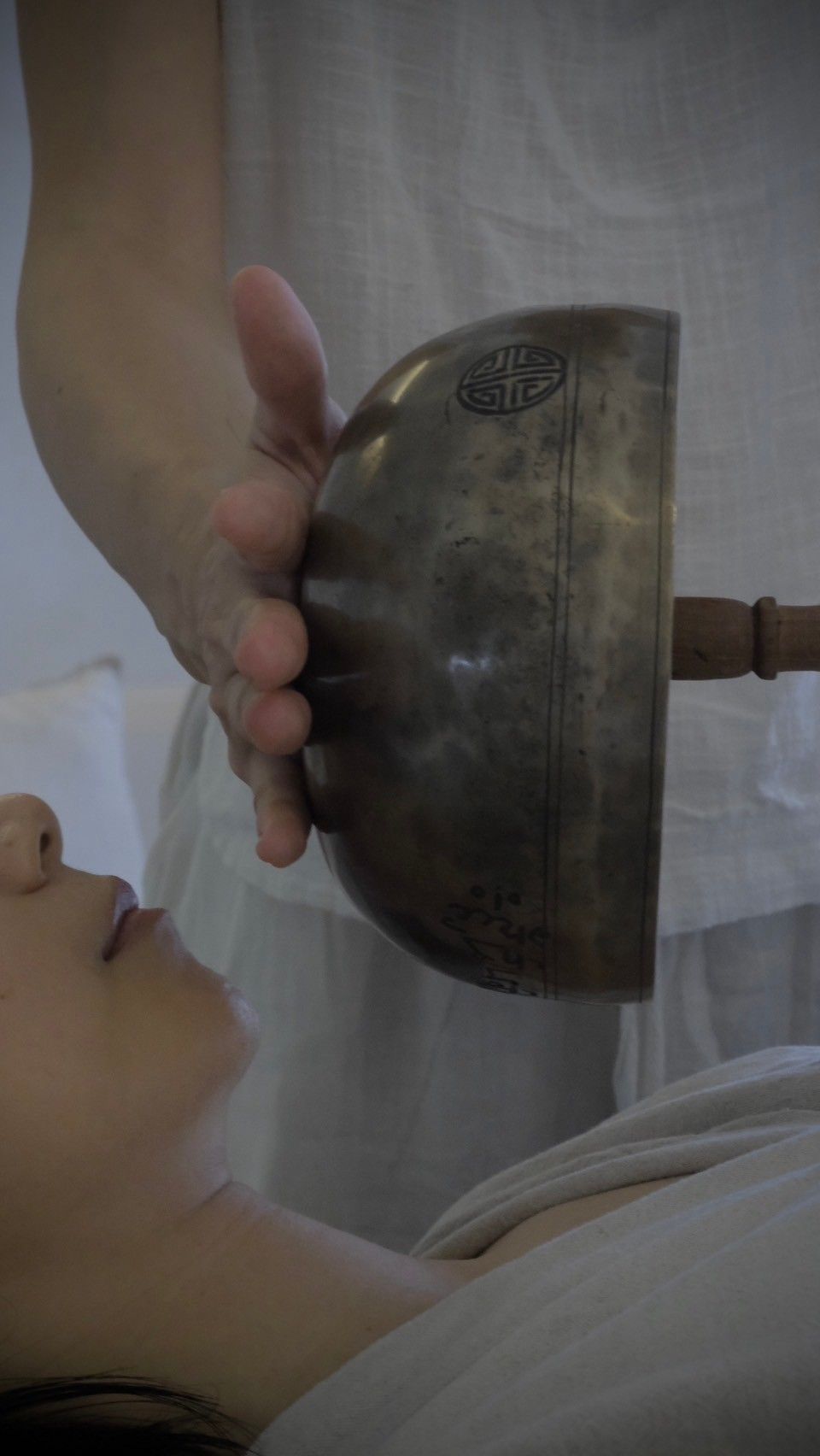 A woman is getting a massage with a bowl on her face.