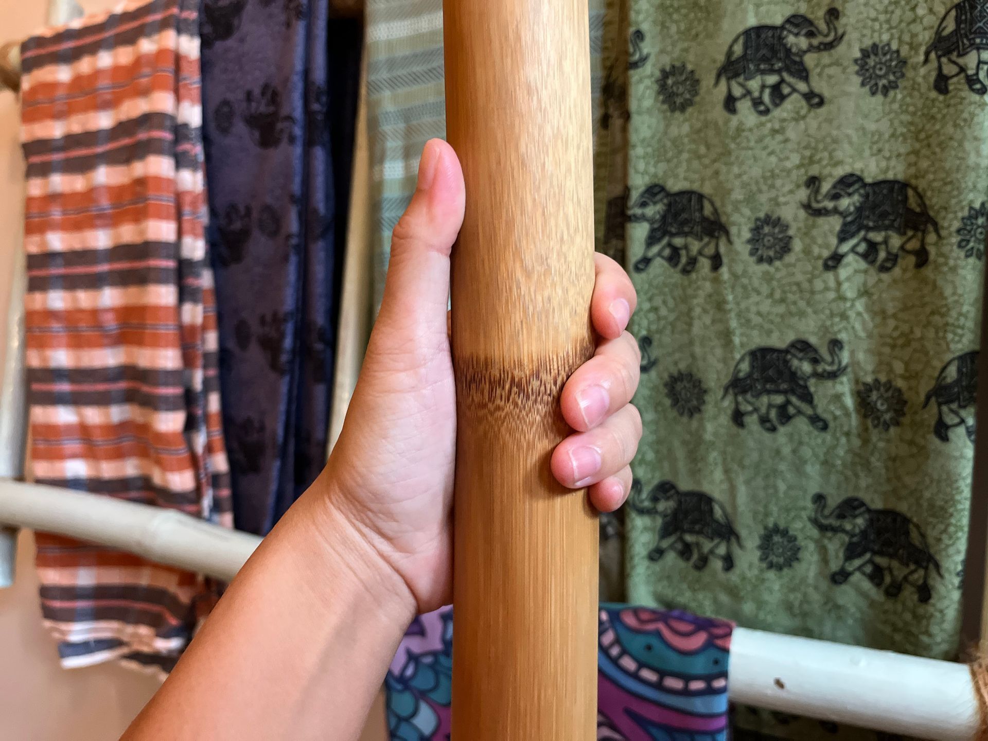 A person is holding a wooden pole with elephants on it