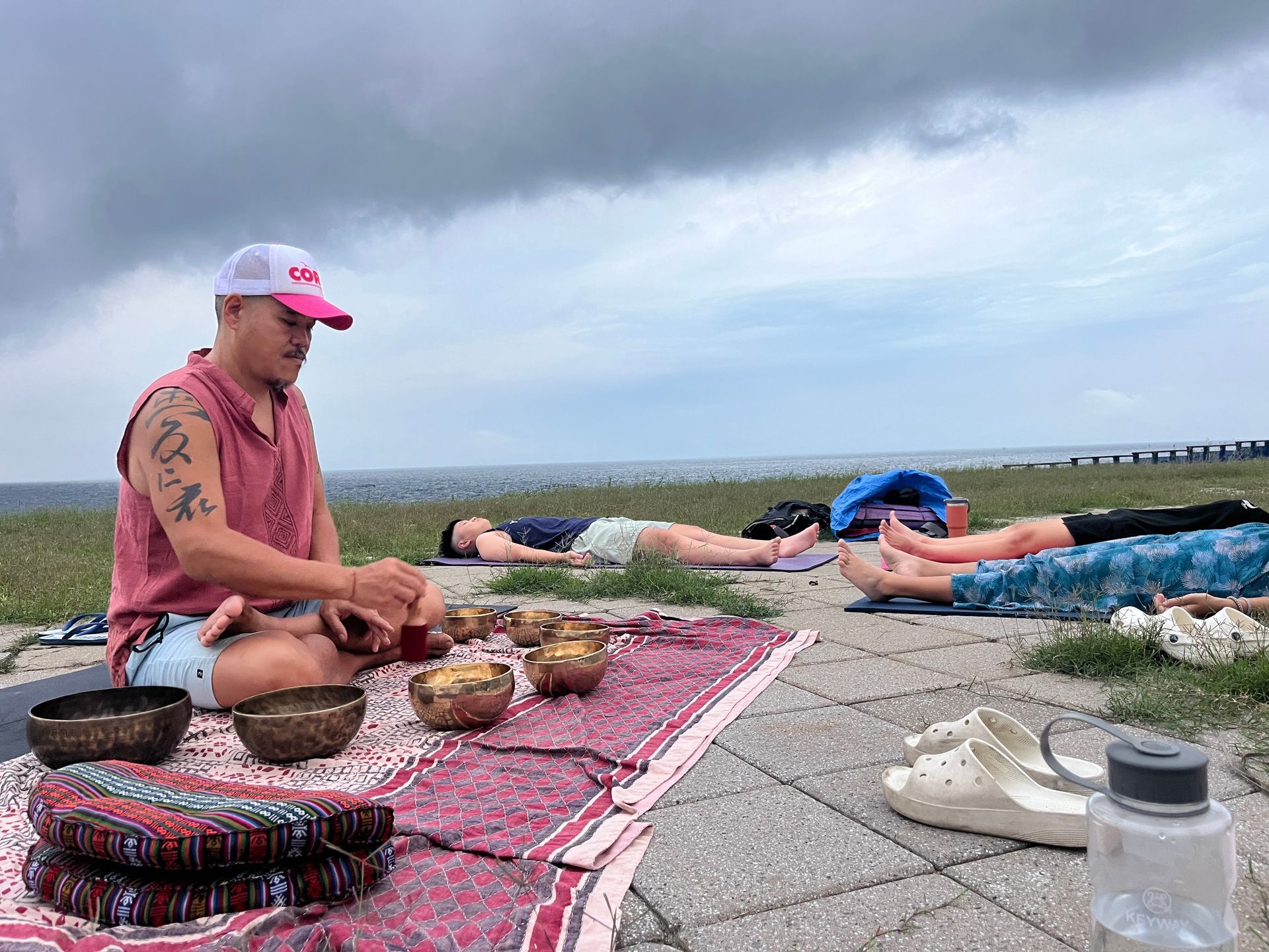 A man is sitting on a blanket next to a group of people laying on the ground.