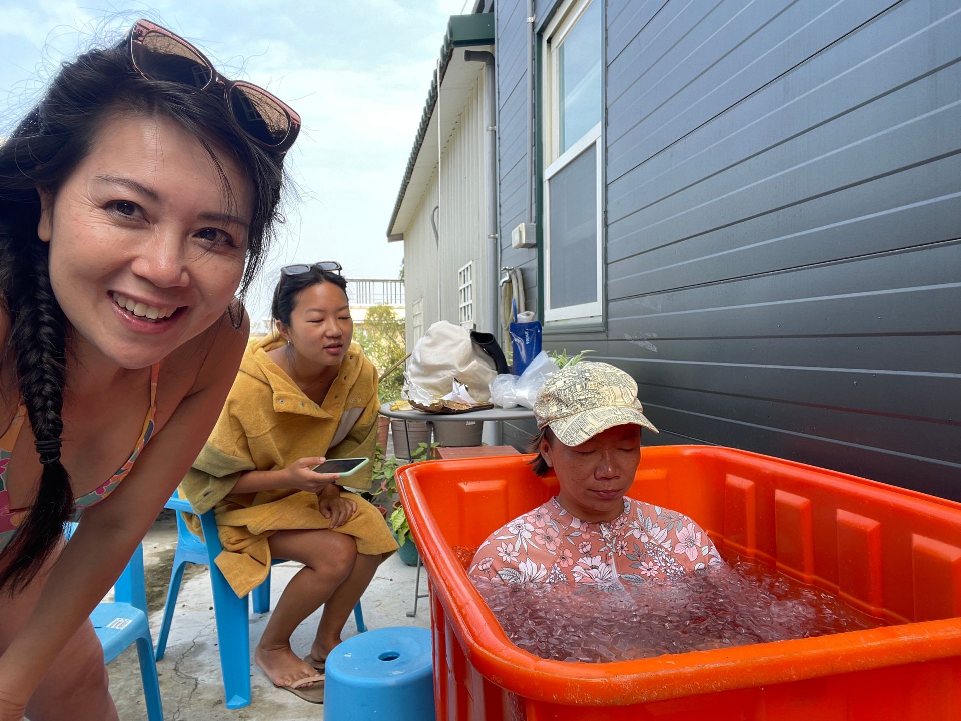 A woman in a bikini is standing next to a woman in an orange tub.