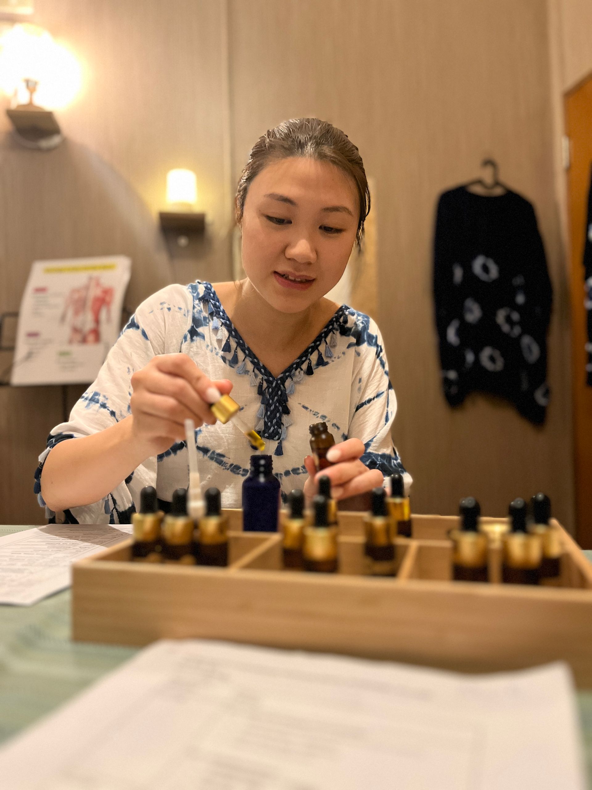 A woman is sitting at a table holding a bottle of oil