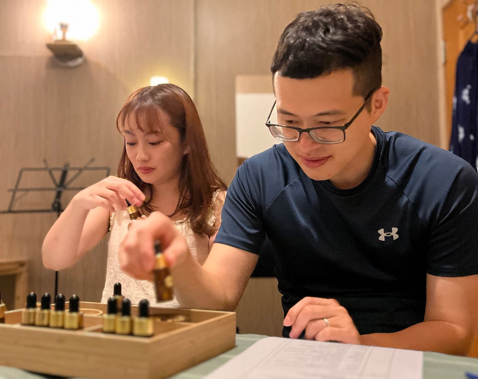 A man and a woman are sitting at a table with bottles of essential oils.