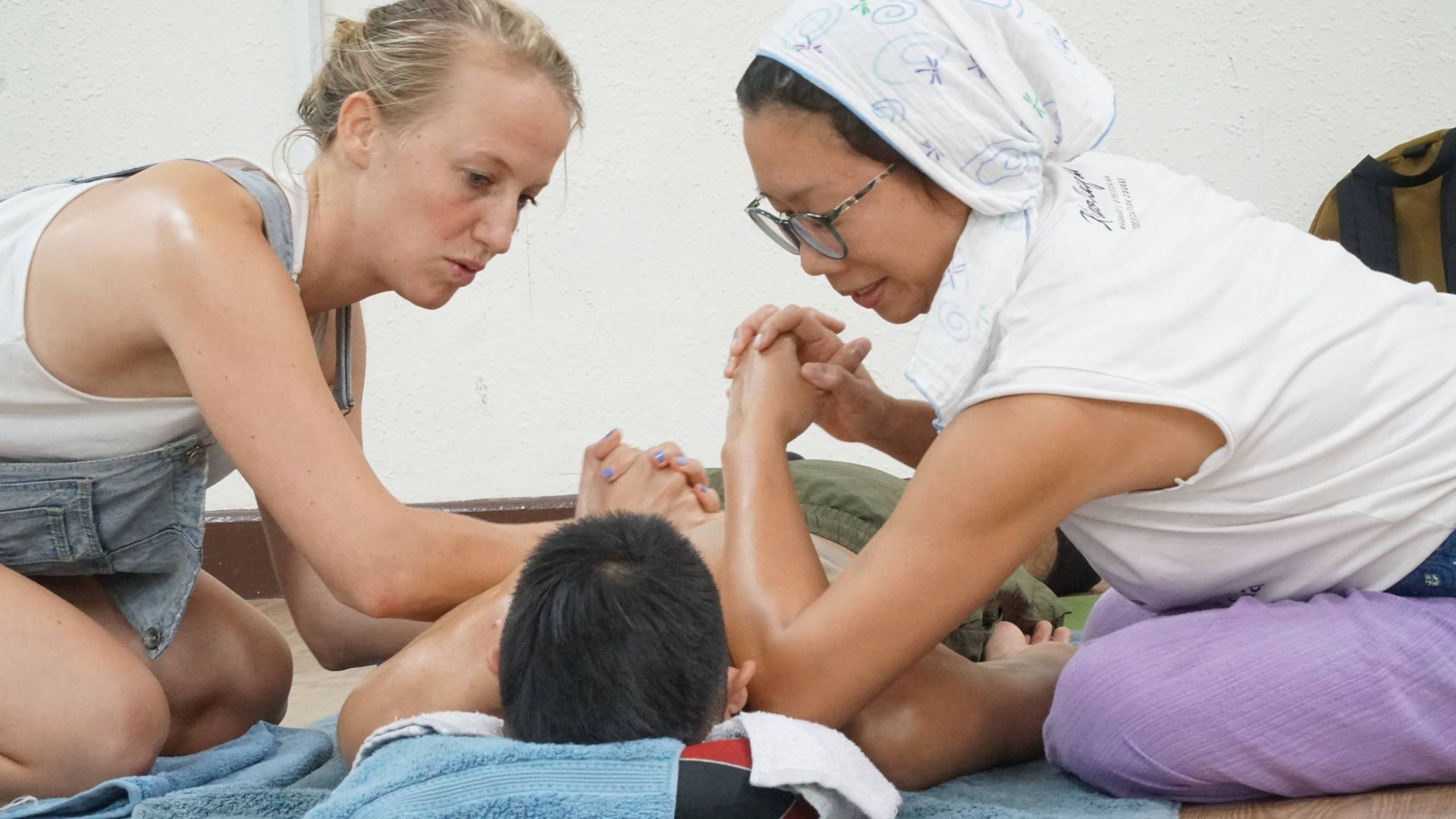 Two women are giving a child a massage on the floor