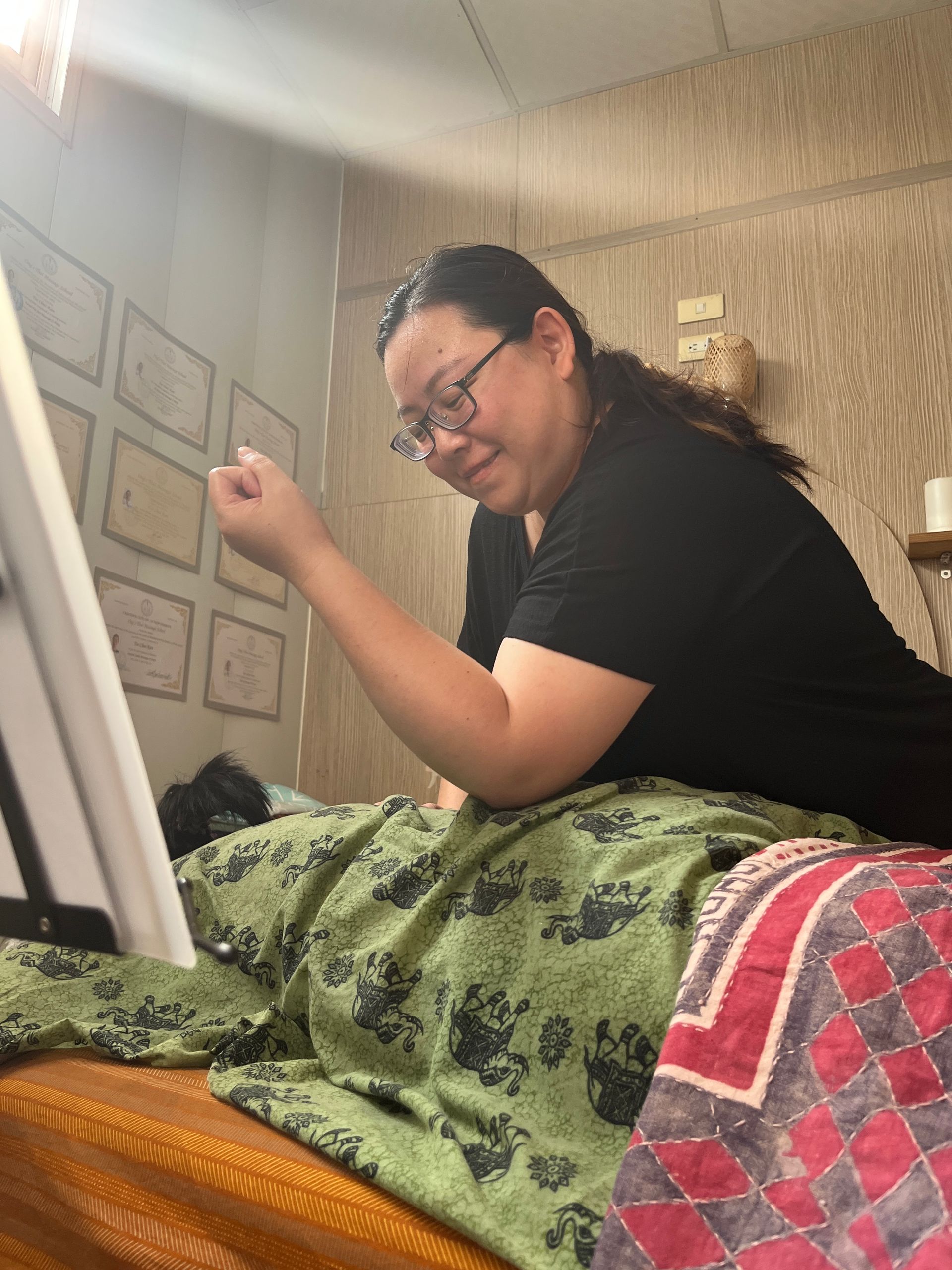A woman is sitting on a bed painting on a canvas.
