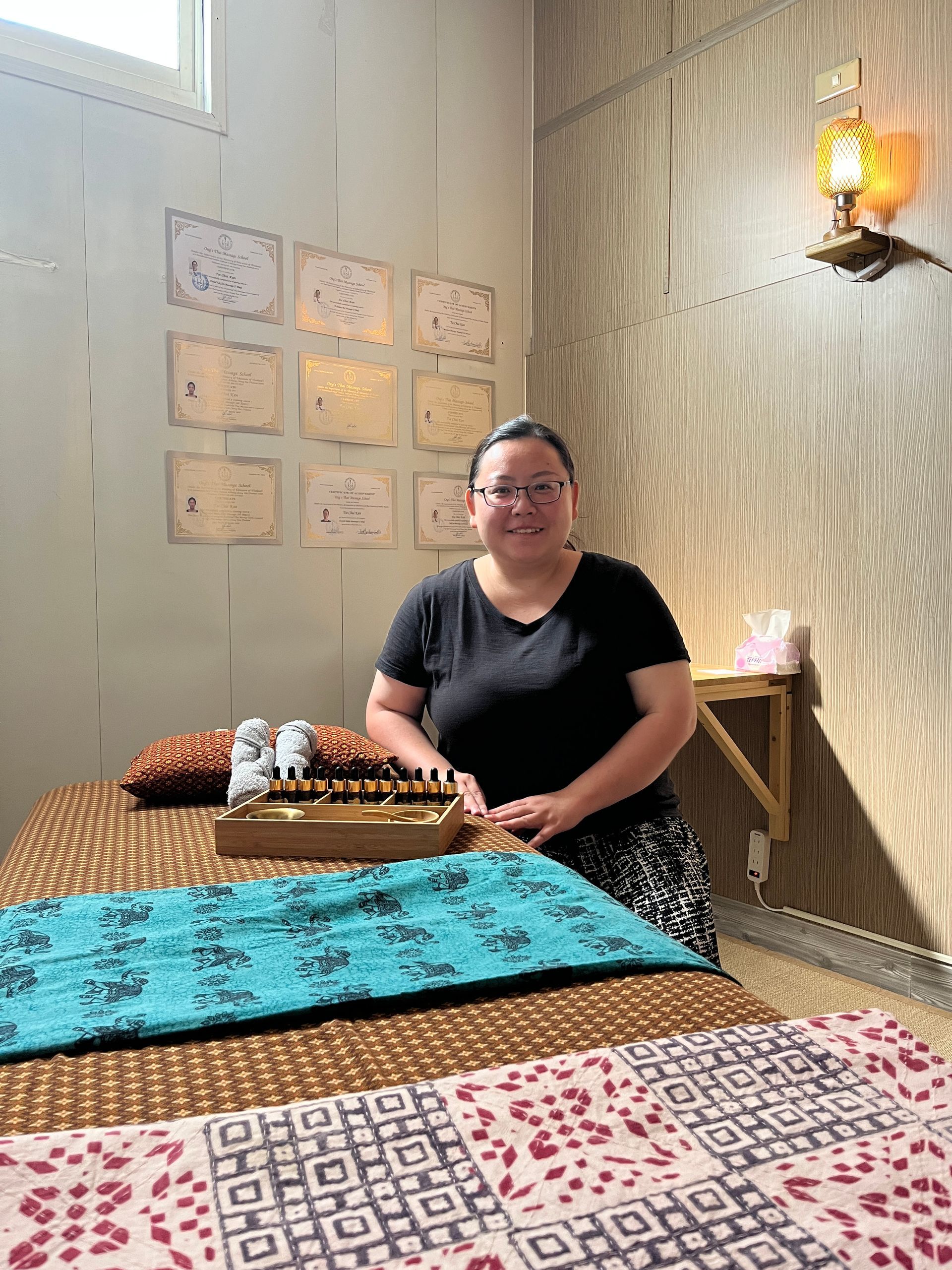 A woman is sitting on a massage table in a room.