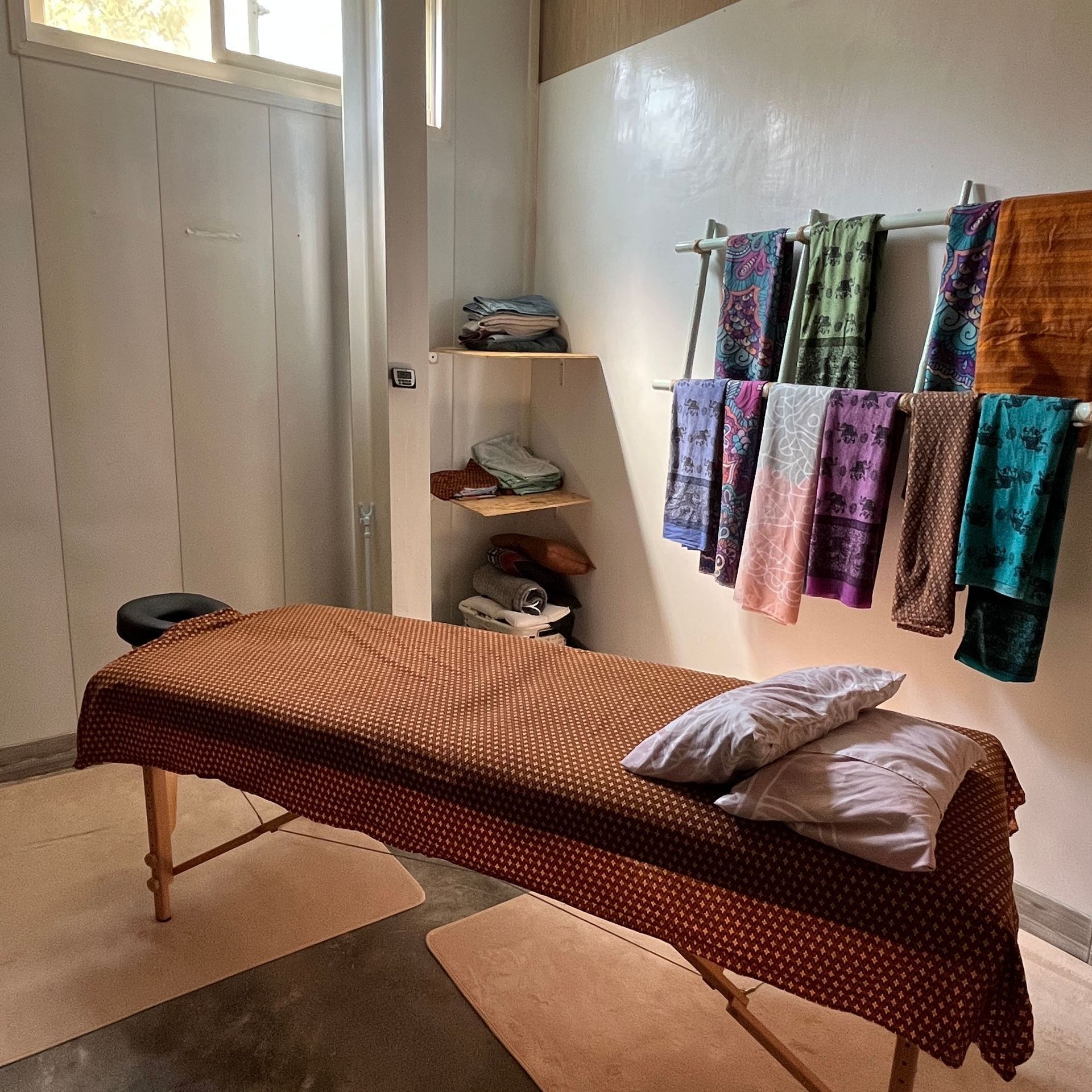 A massage table in a room with towels hanging on the wall