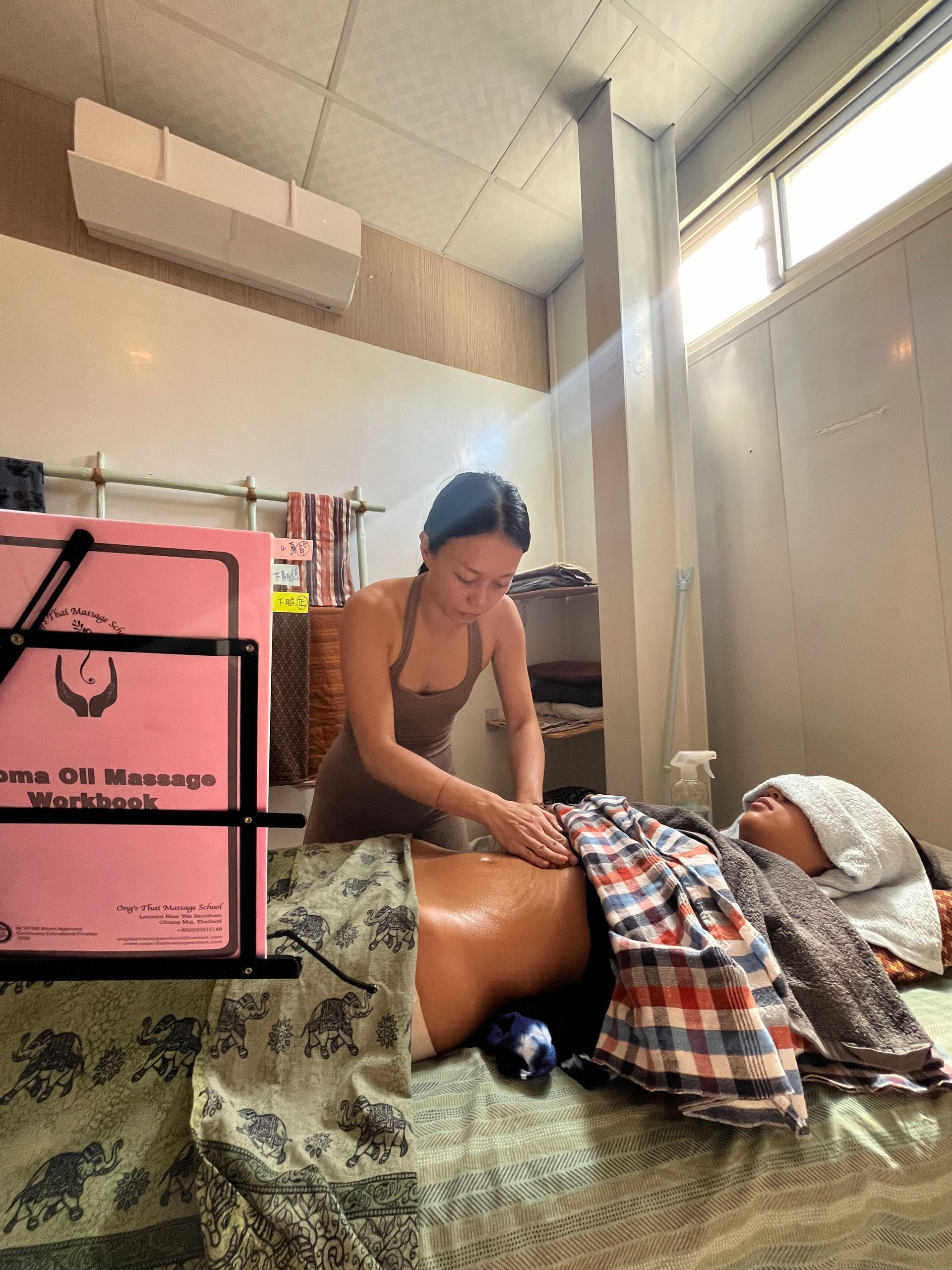 A woman is giving a massage to a man laying on a bed.