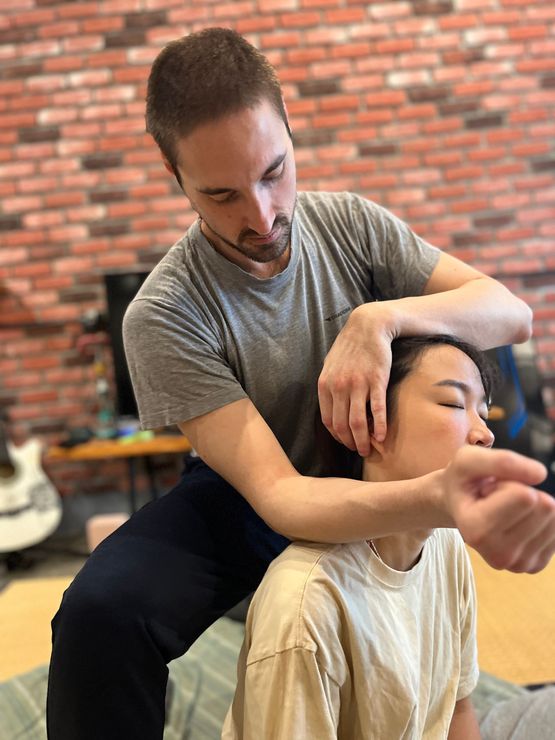 A man is giving a woman a massage in front of a brick wall.