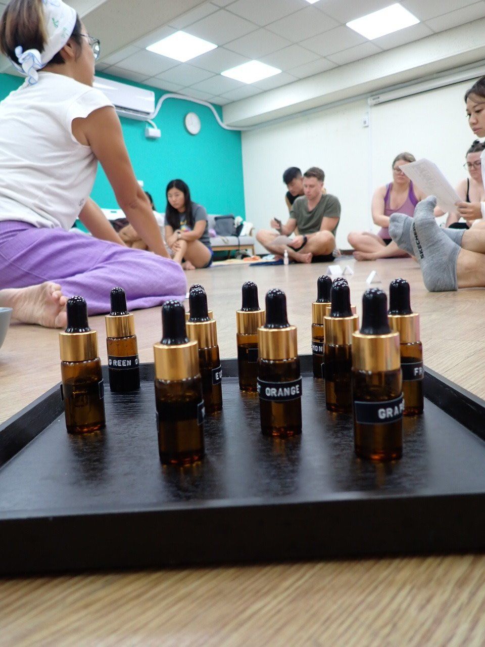 A group of people are sitting on the floor with a tray of essential oils